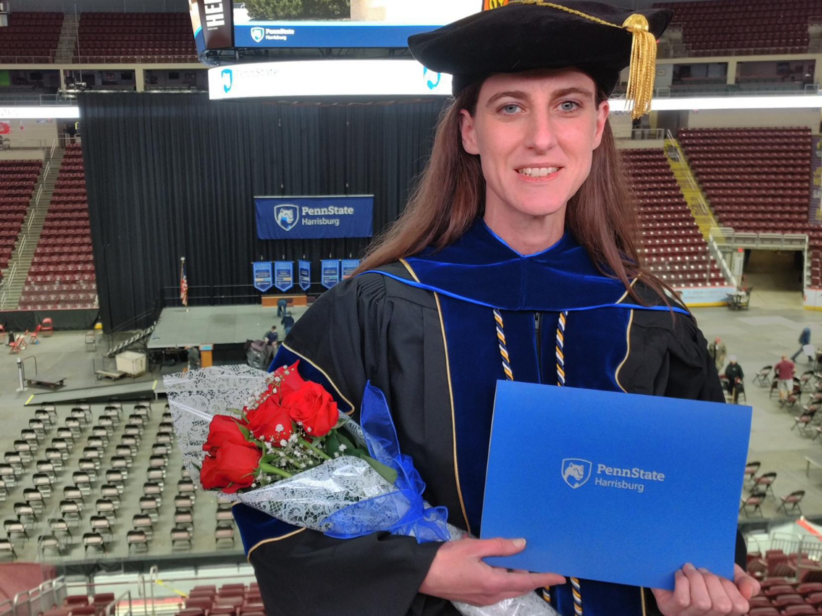 Jessica Sheets in graduation attire, holding a diploma and roses