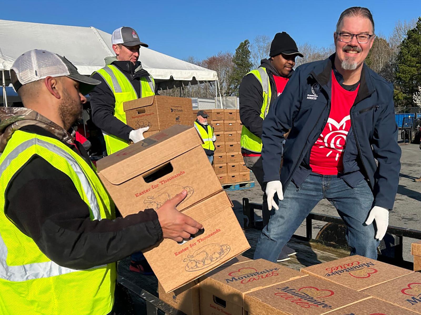 A man helping carry boxes outdoors.