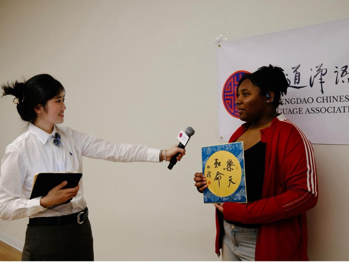 A student is interviewed about their experience while holding a piece of calligraphy art. 