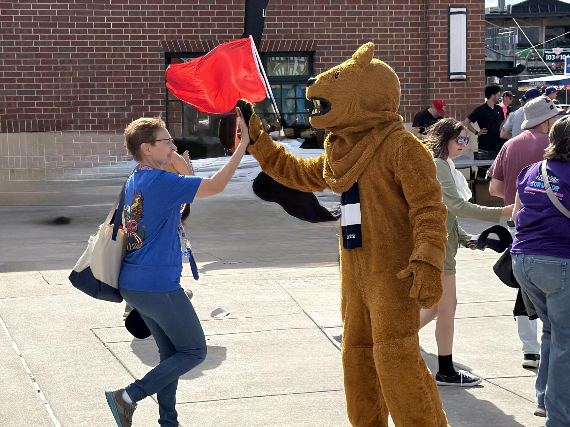 a woman and the nittany lion giving a high five