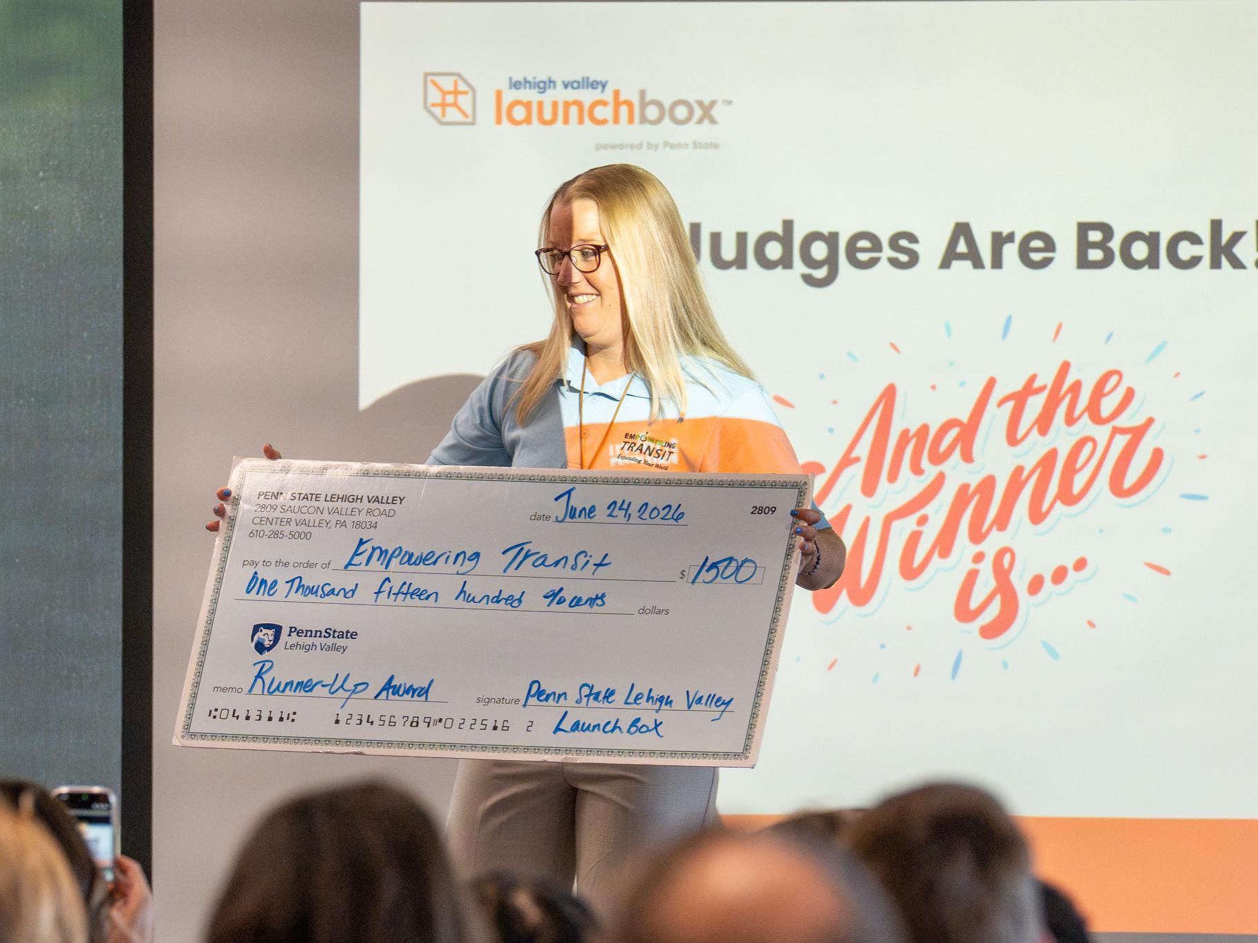 woman standing holding a large check