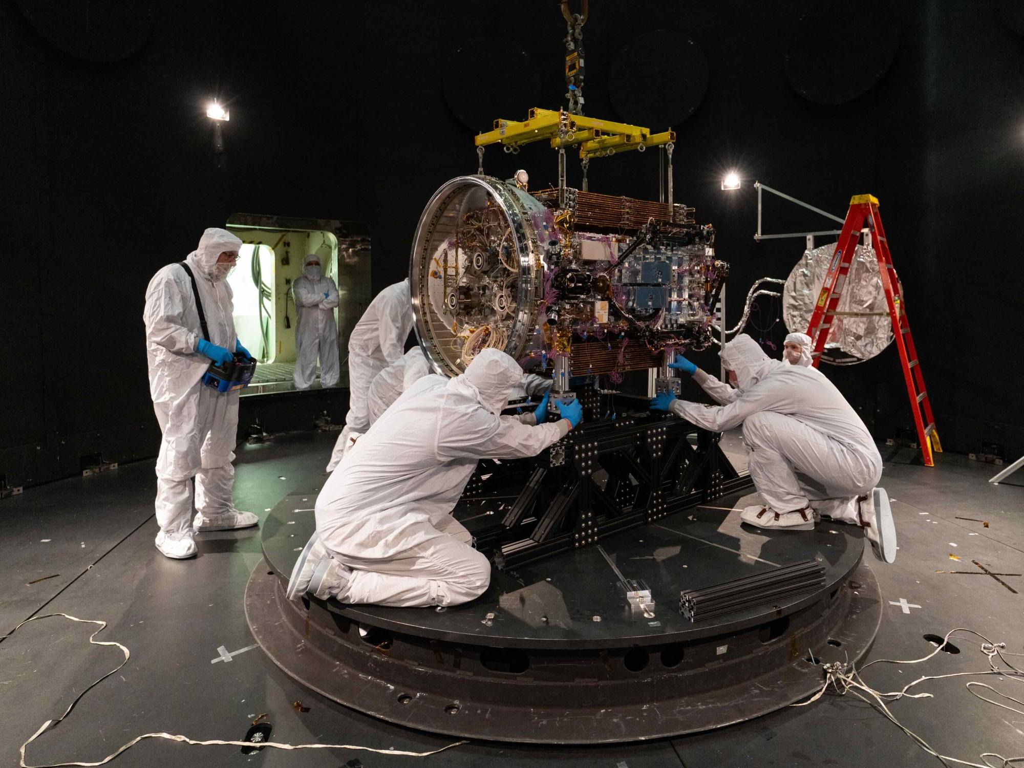 several people in clean suits work on instrument