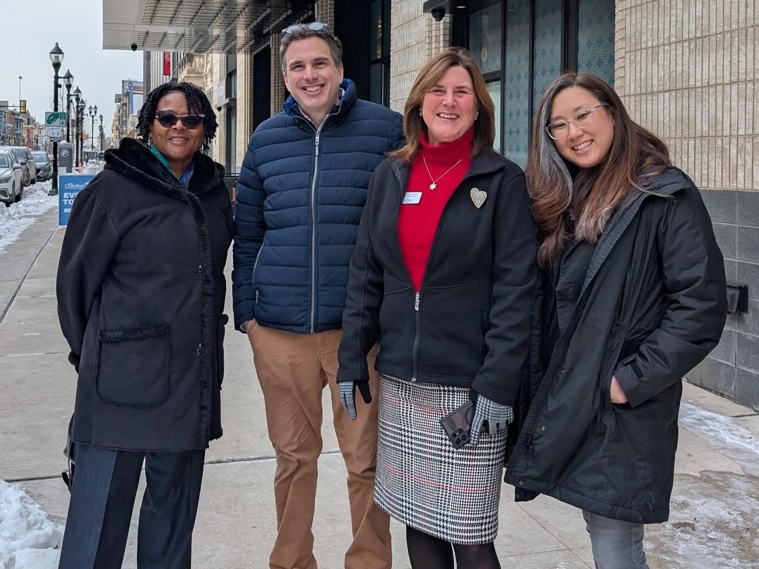 four people standing next to each other on a street