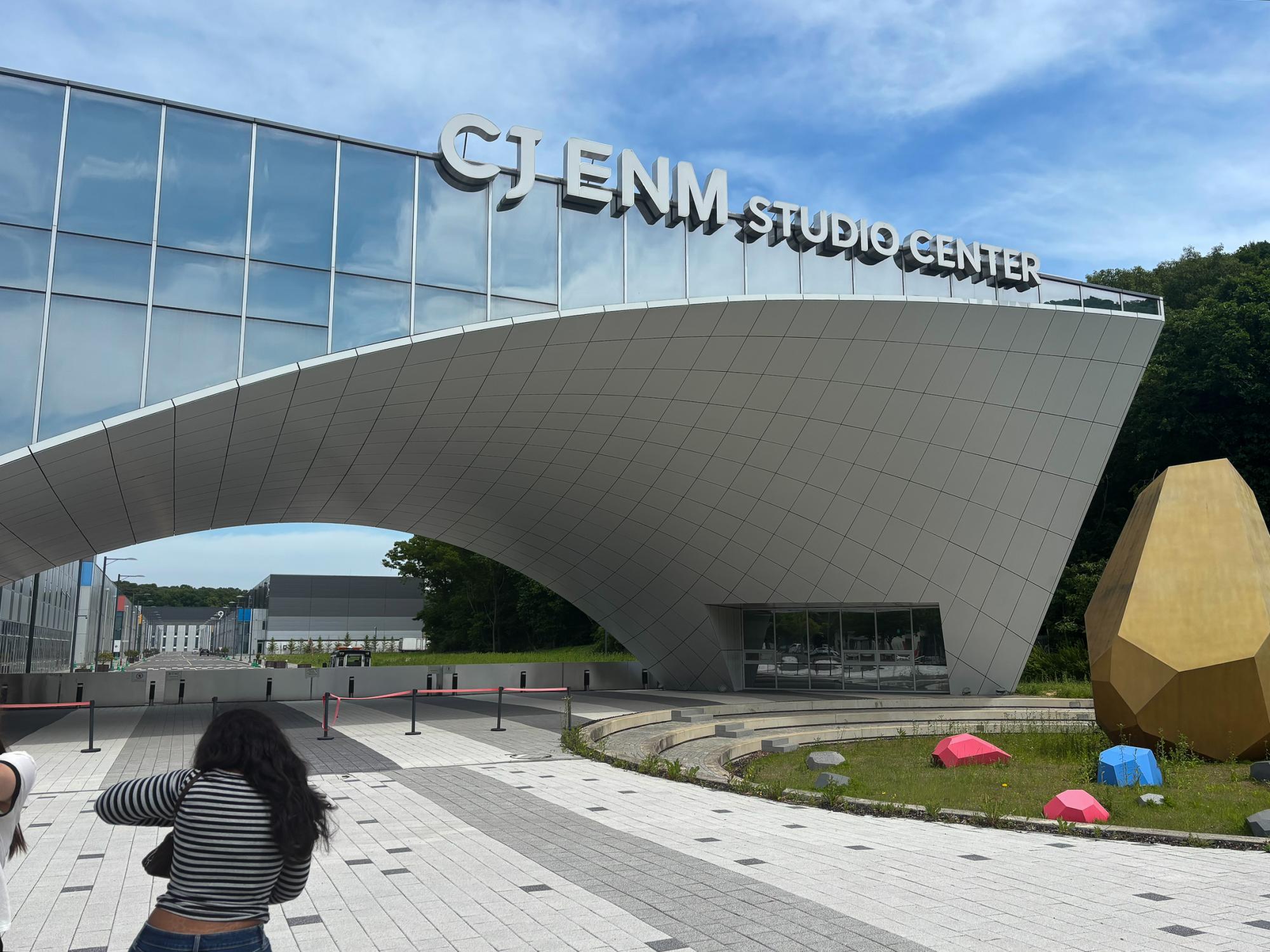 A wide shot of the CJ ENM Studio’s modern building with metallic planes and large windows.