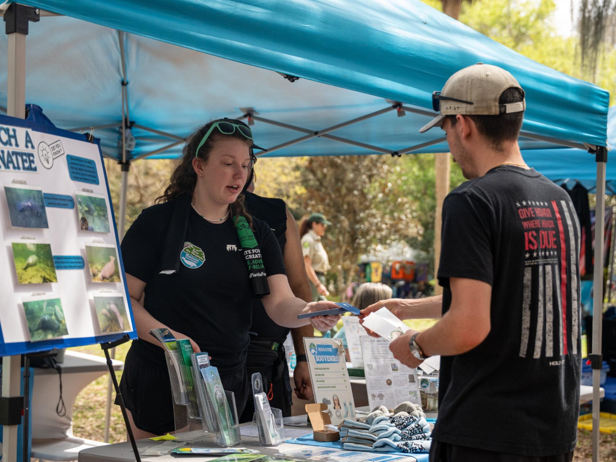 A student shares educational materials with a visitor while volunteering at the Save the Manatee Club.