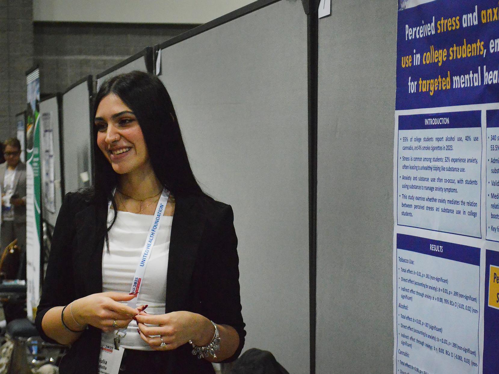 Giulia Cantella stands next to her research poster at a conference