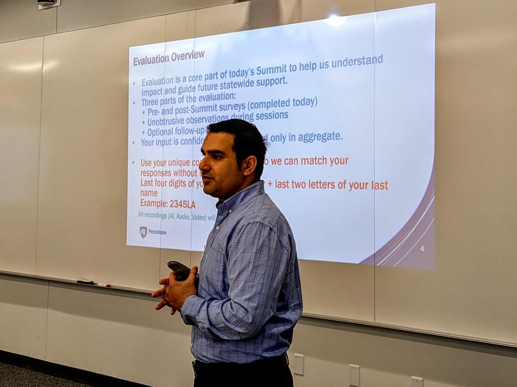 A man stands near a projection screen and gives a presentation.