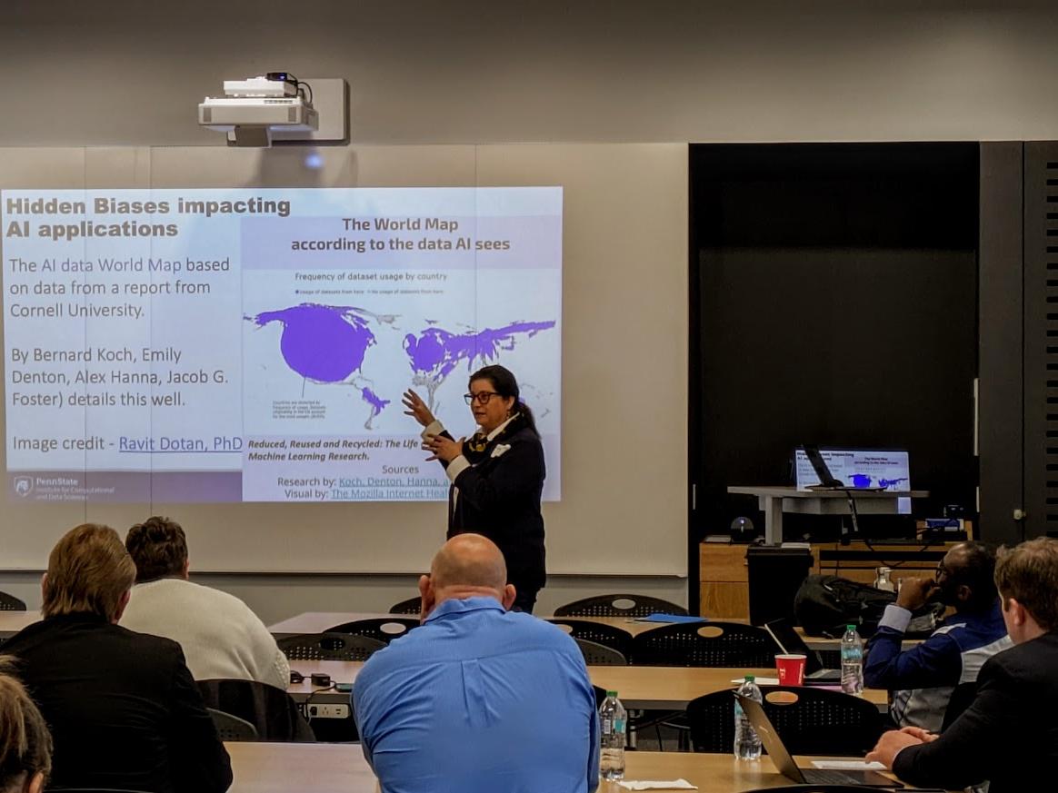 A woman stands near a projection screen and gives a presentation.