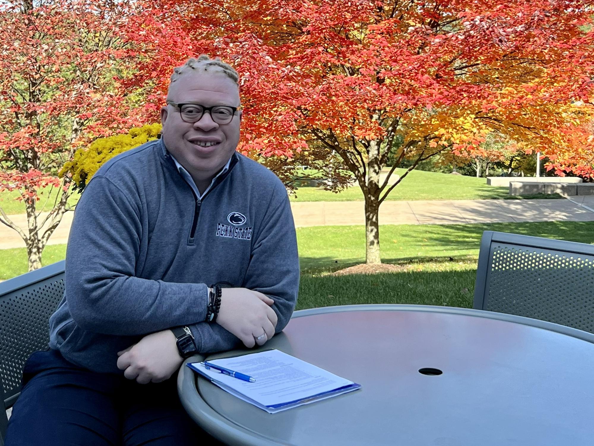 Penn State Behrend alumnus Brandon McGraw sits at an outdoor table during a visit to campus.