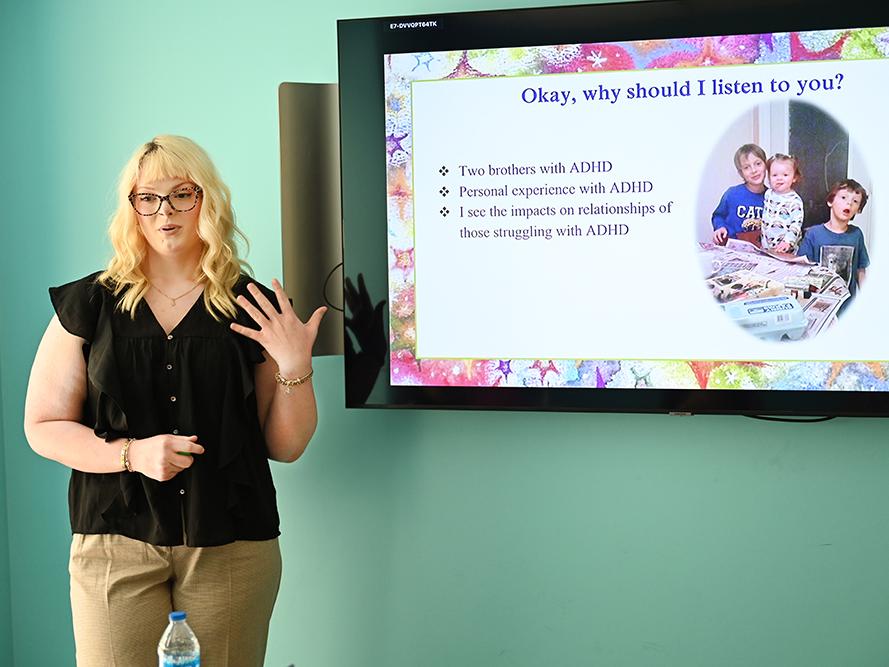A high school student in a dark shirt gives a presentation.