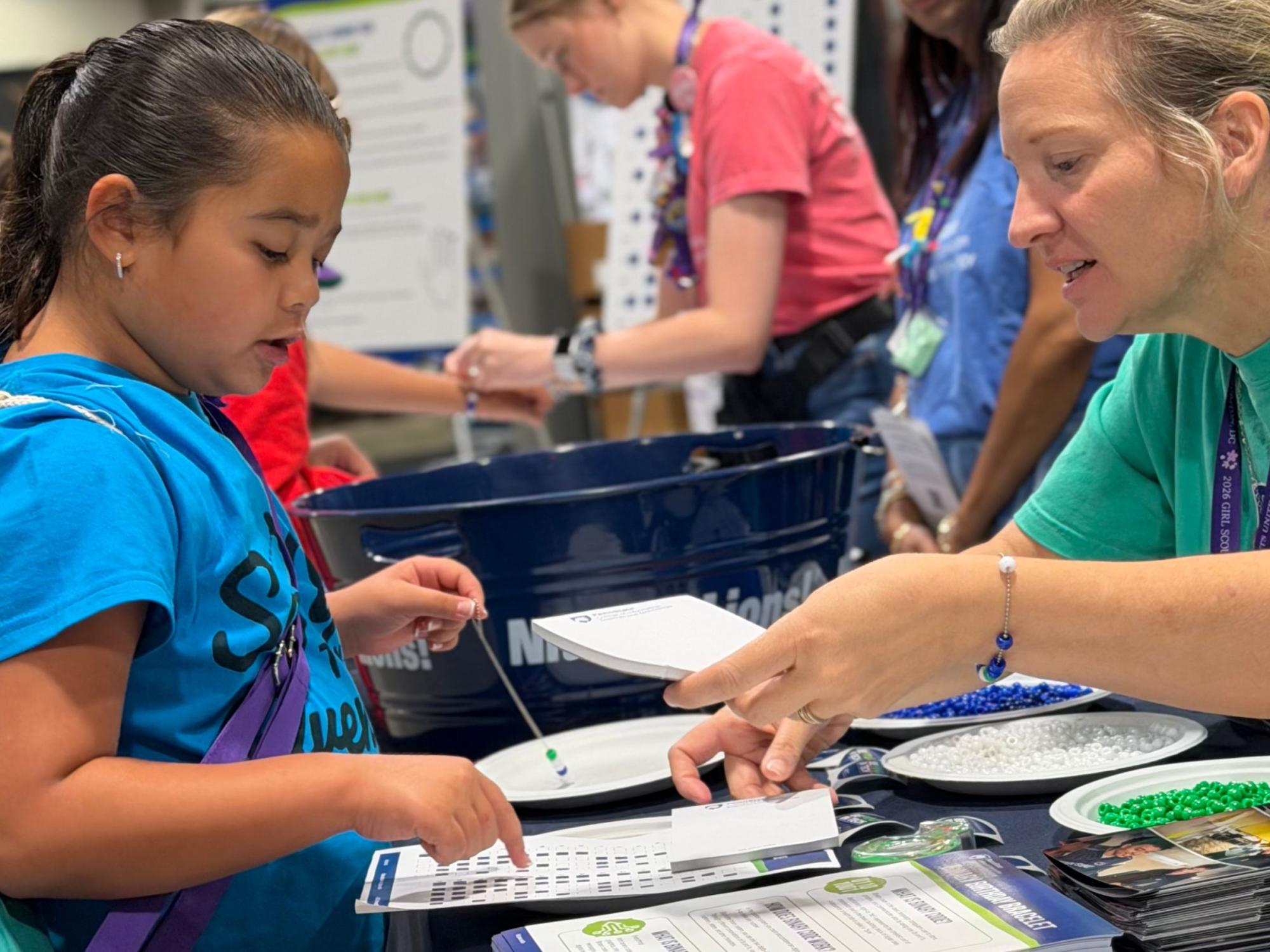 Adult shows child how to make bracelet out of binary beads