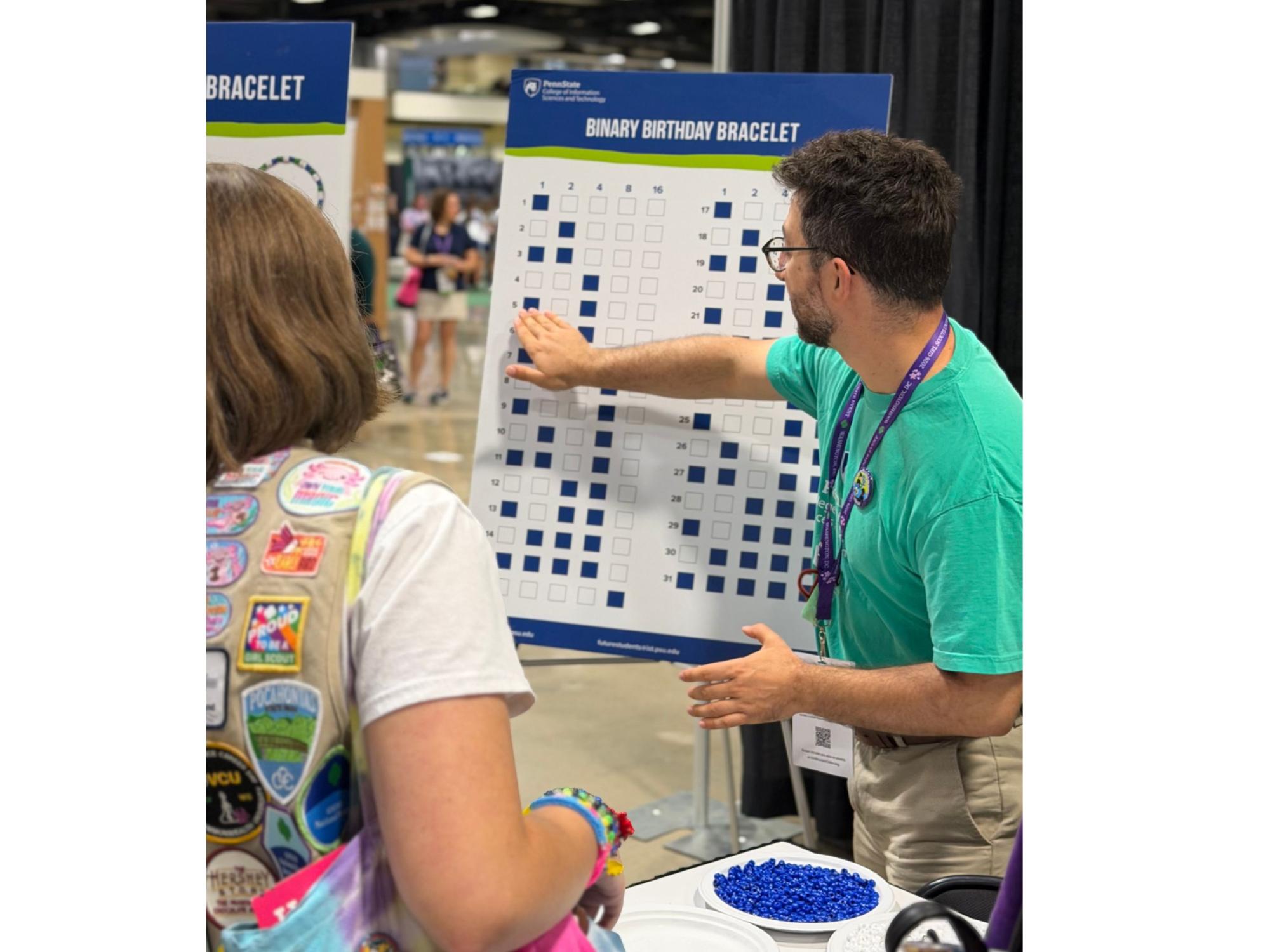 teacher demonstrates coding activity to scout leader