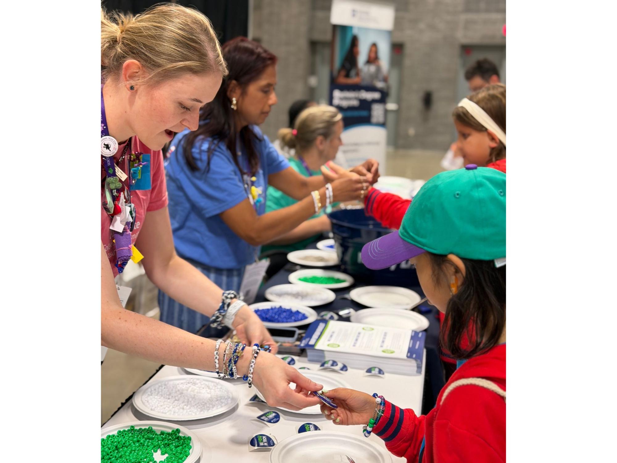 adults share swag and demonstrate activities at Girl Scouts convention booth