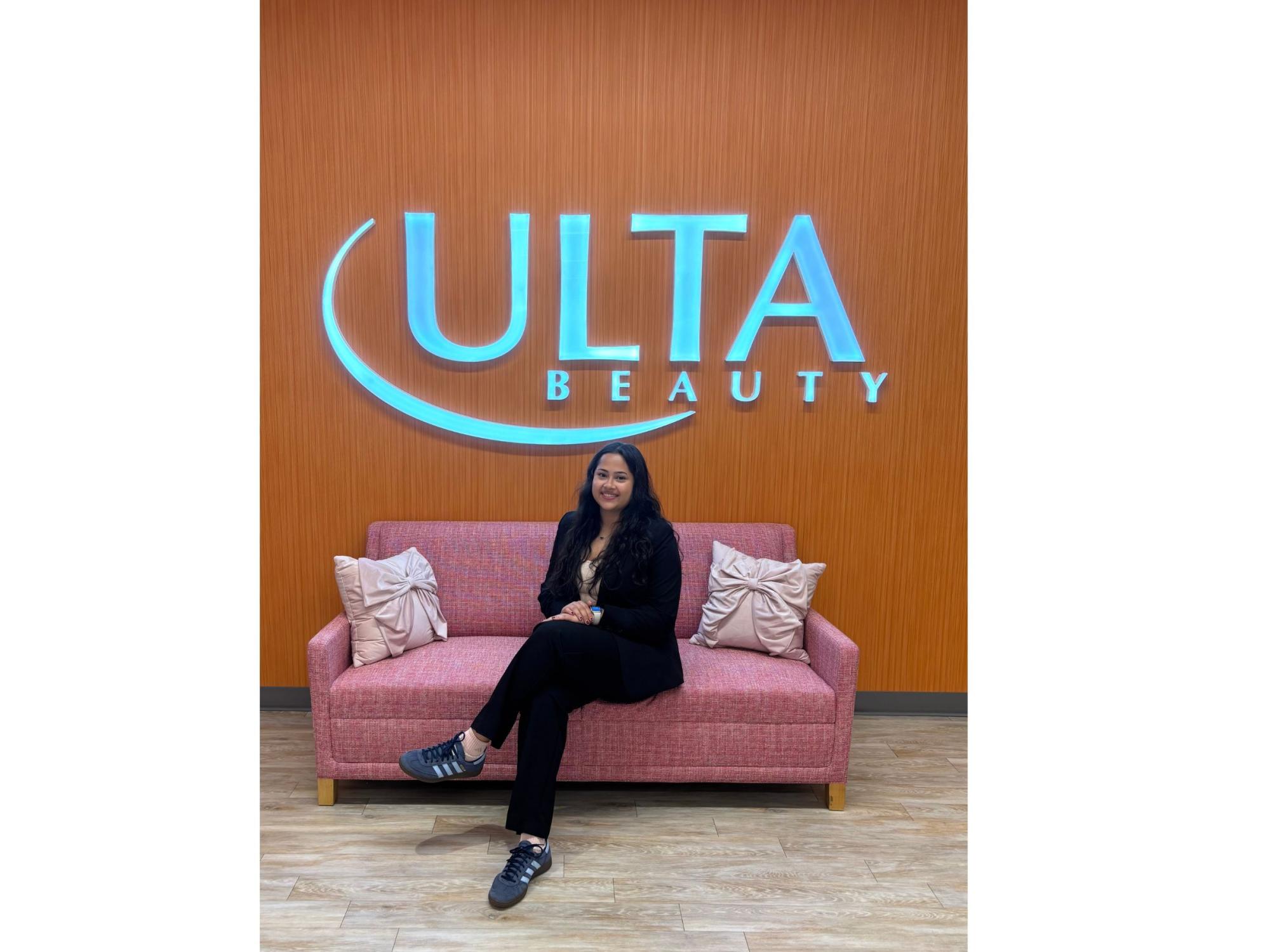 young adult with black hair sits on a sofa in front of an ulta beauty sign