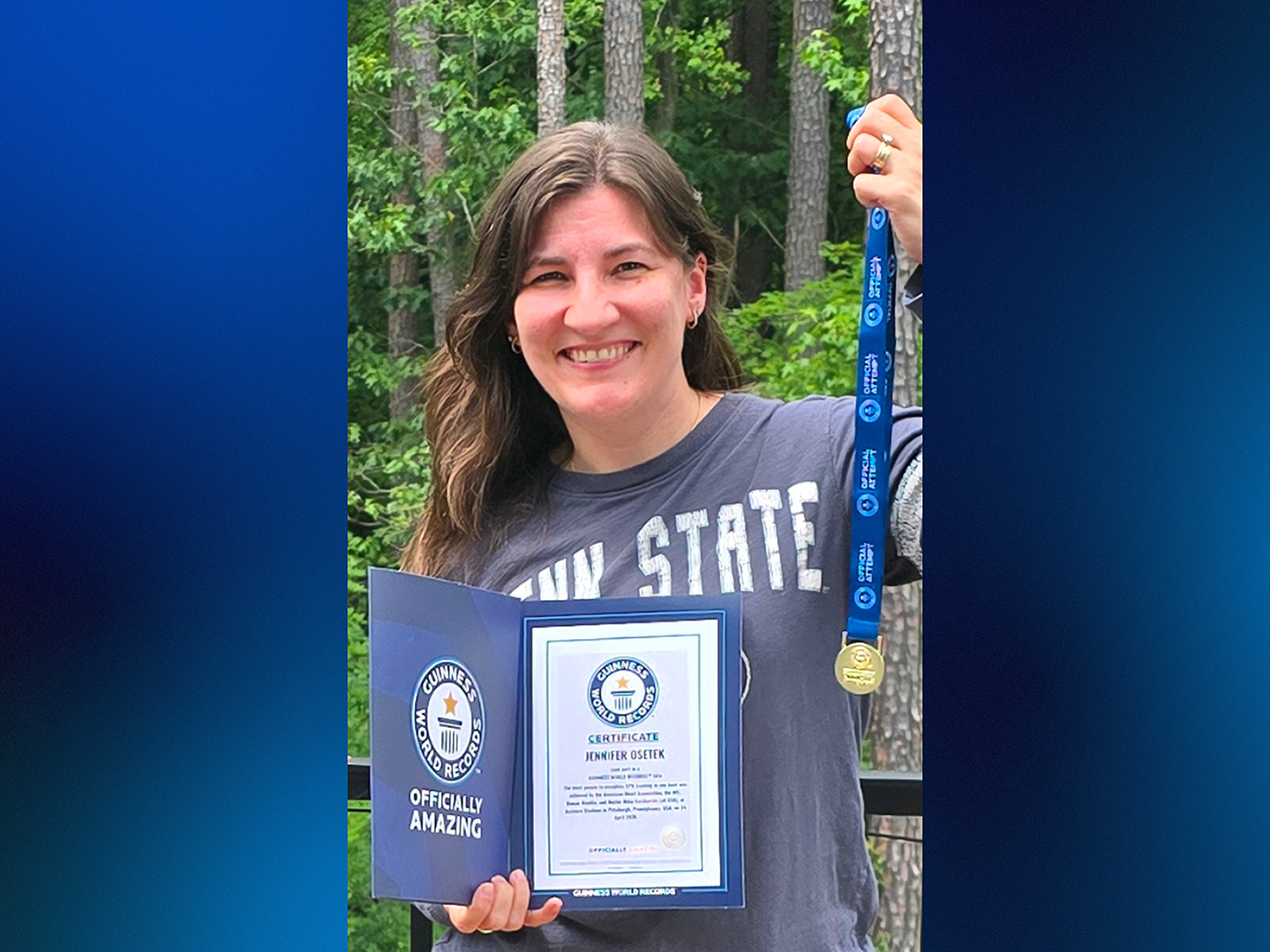 A woman holds a meal and certificate in front of trees.
