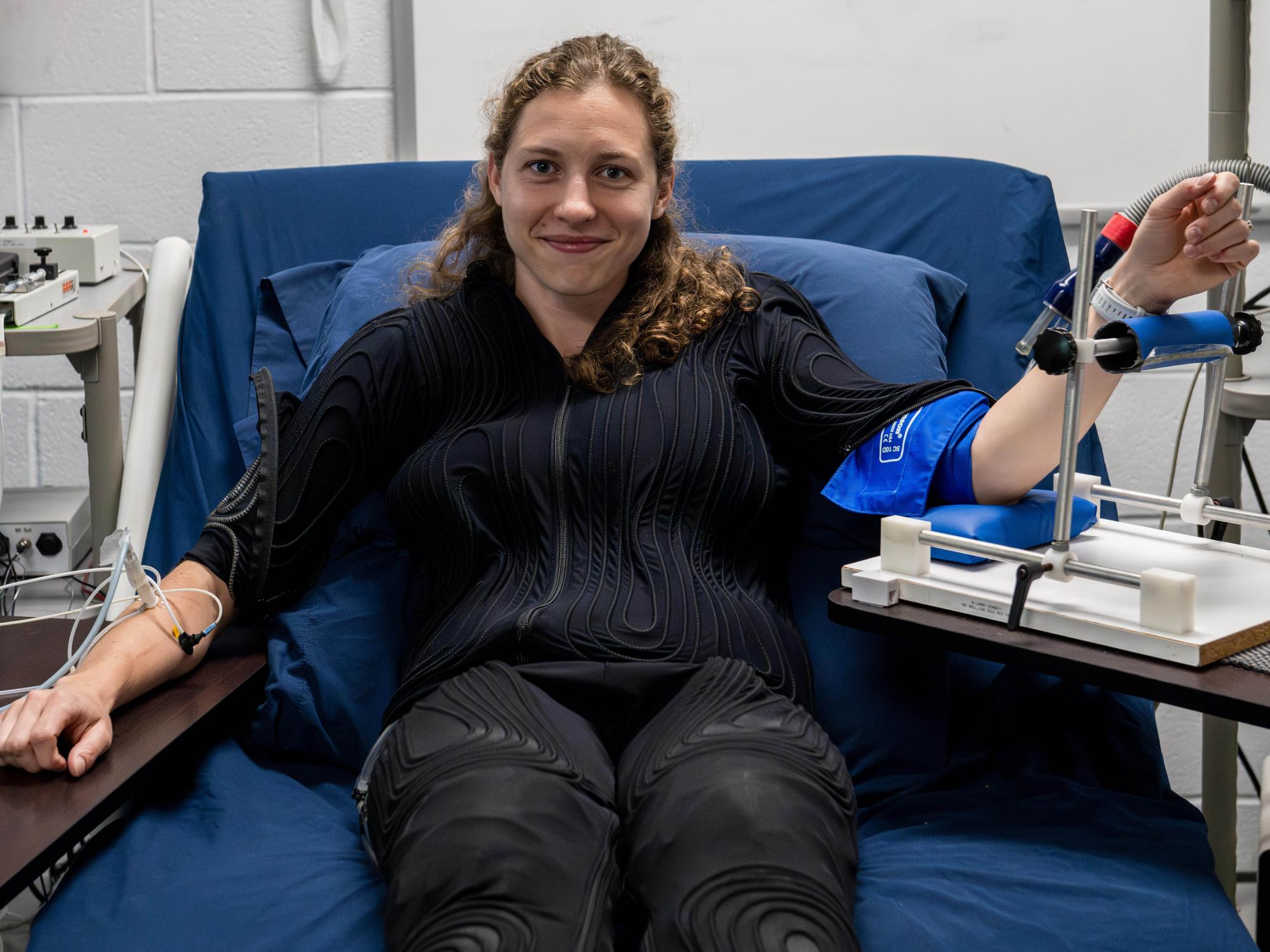 Kat Fisher in the experiment's suit on a hospital bed with sensors connected to both arms