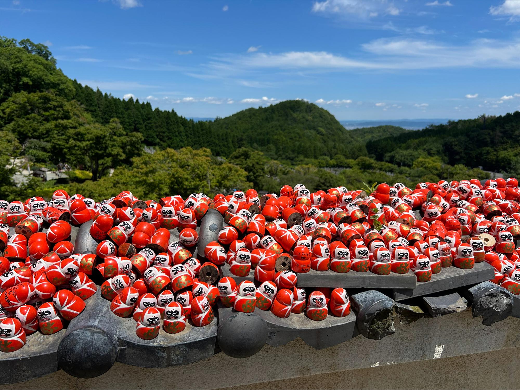 Kaylin Lamaute visits miniature red and white figurines known as Daruma dolls