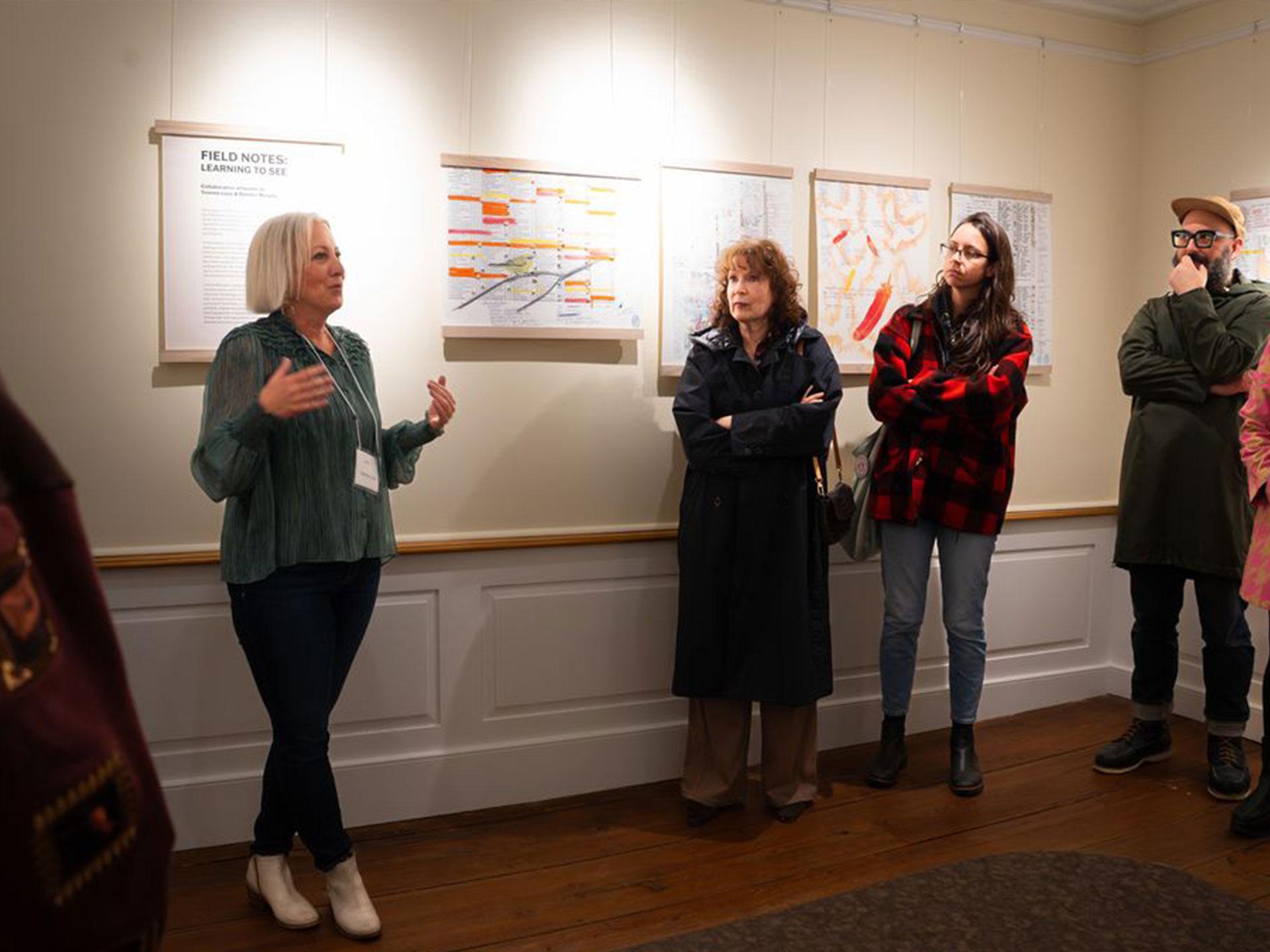 woman talking to a group of people in an art gallery