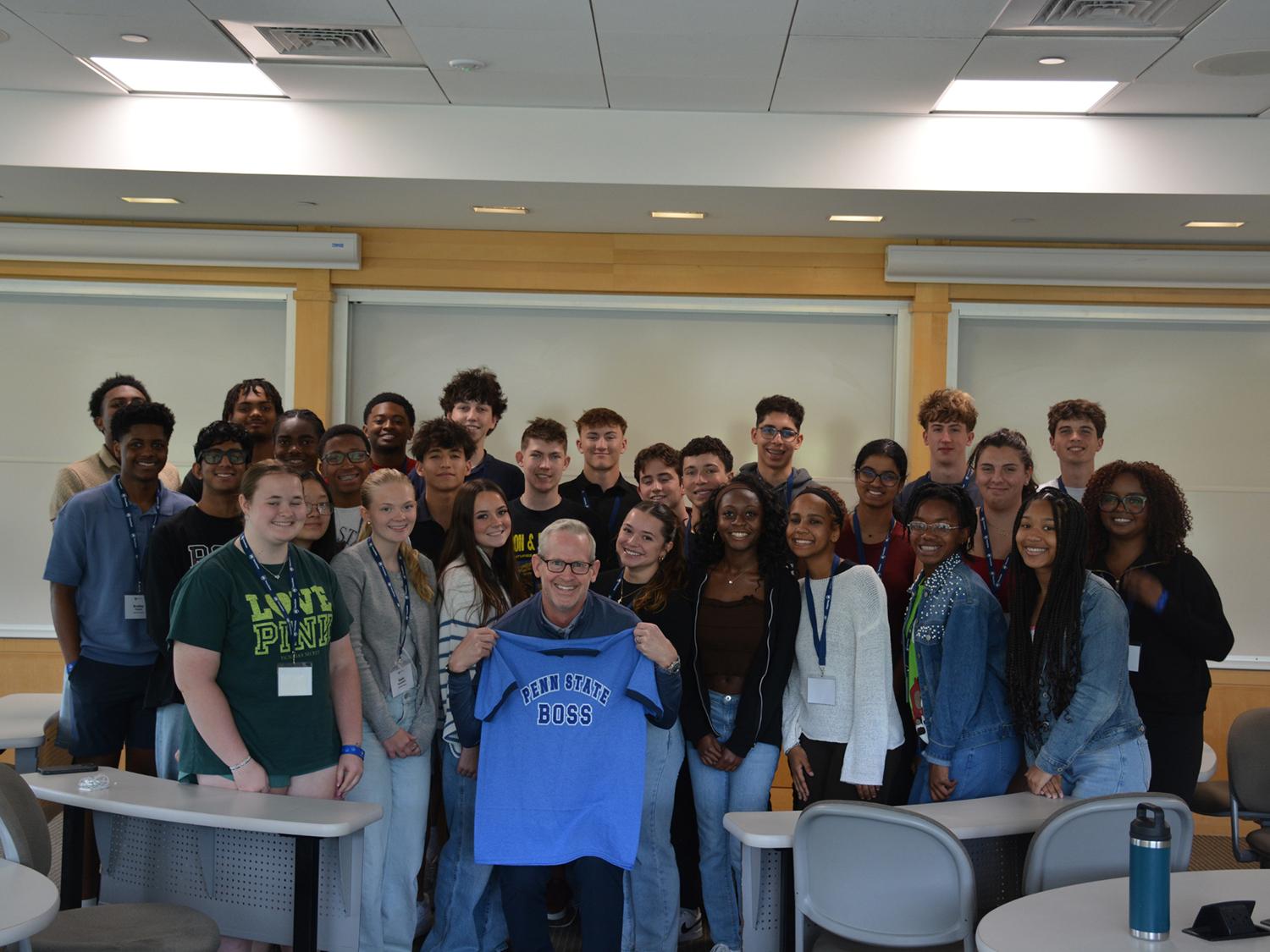 Smeal Dean Corey Phelps holds up a Penn State BOSS T-shirt as he poses with the 2026 cohort. 