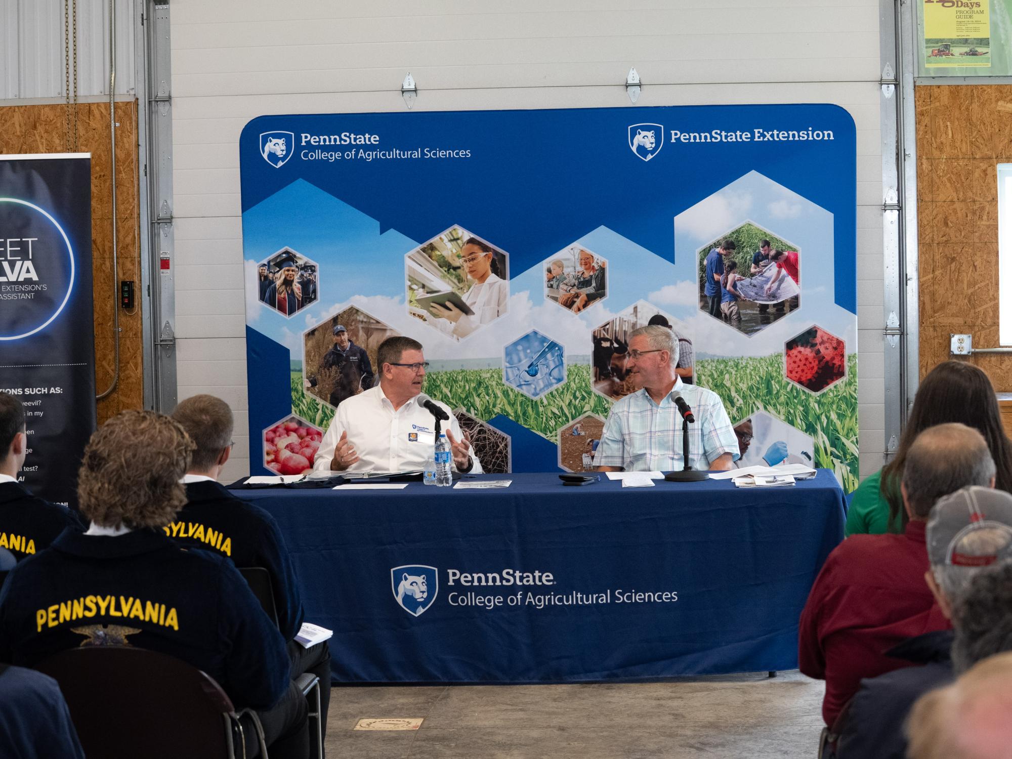 Two individuals sit on a panel in with signage branded "Penn State College of Agricultural Sciences"