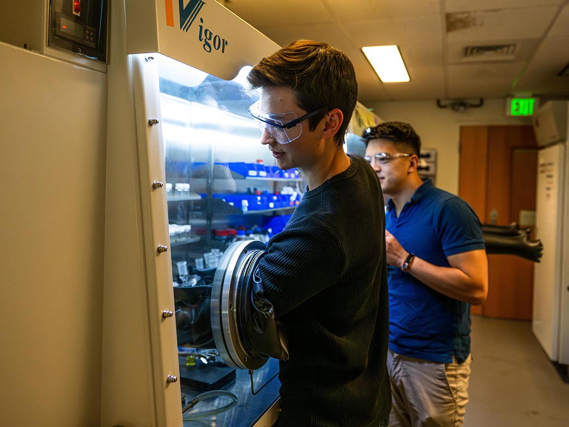 Two researchers working in chemistry lab hood.