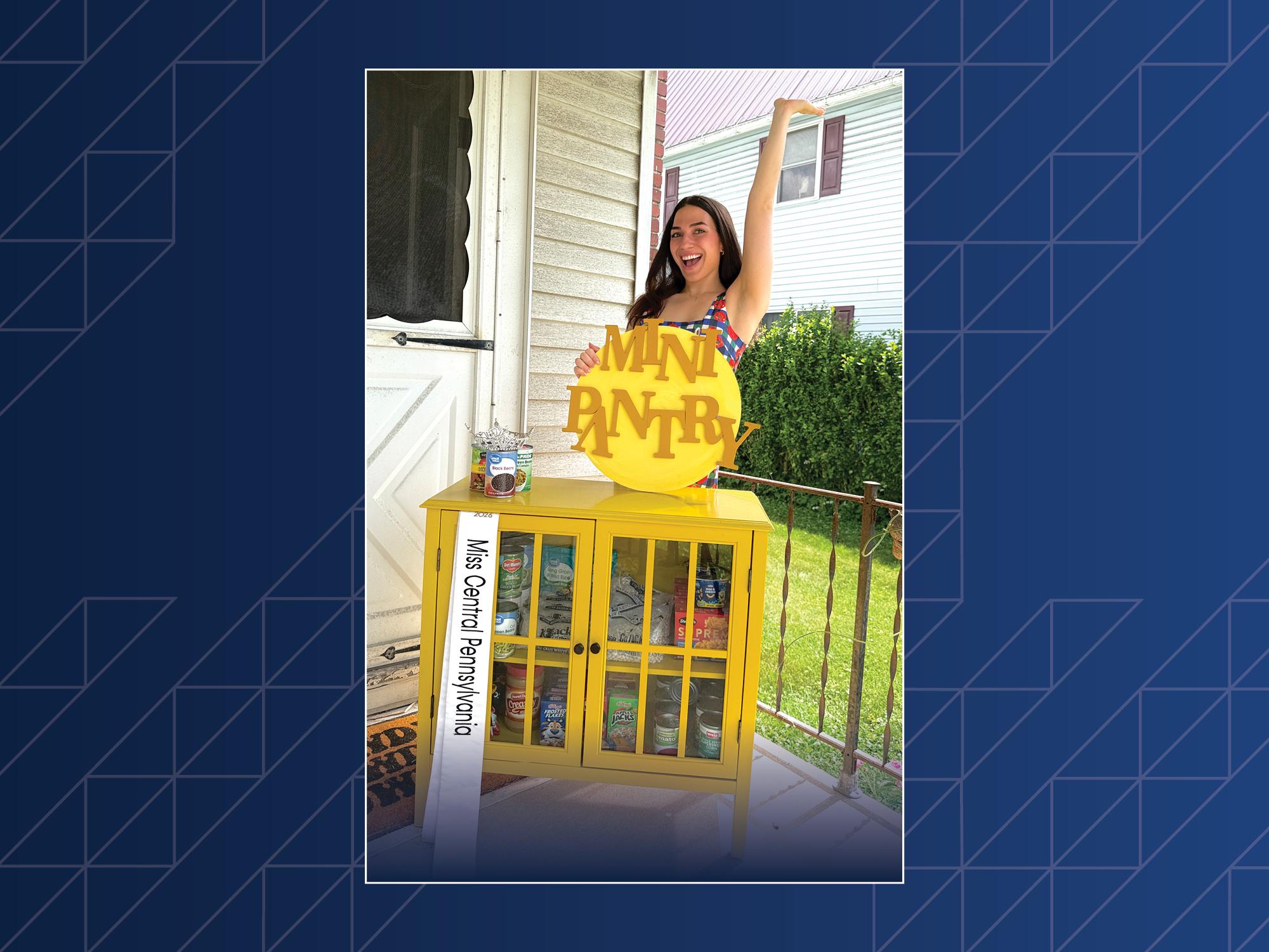 A woman poses in front of a food pantry on a porch.