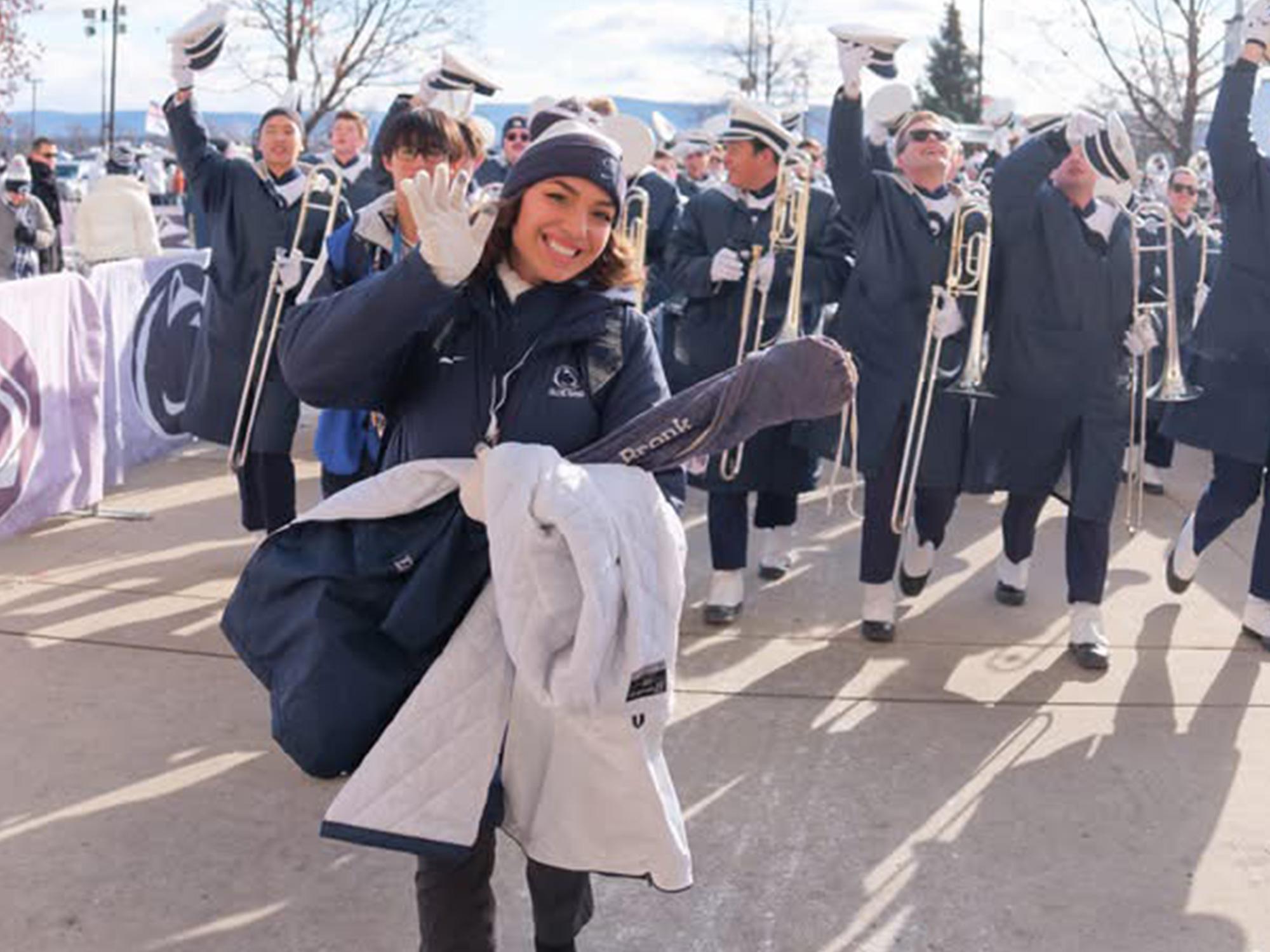A woman holds a blanket in front of a marching band.
