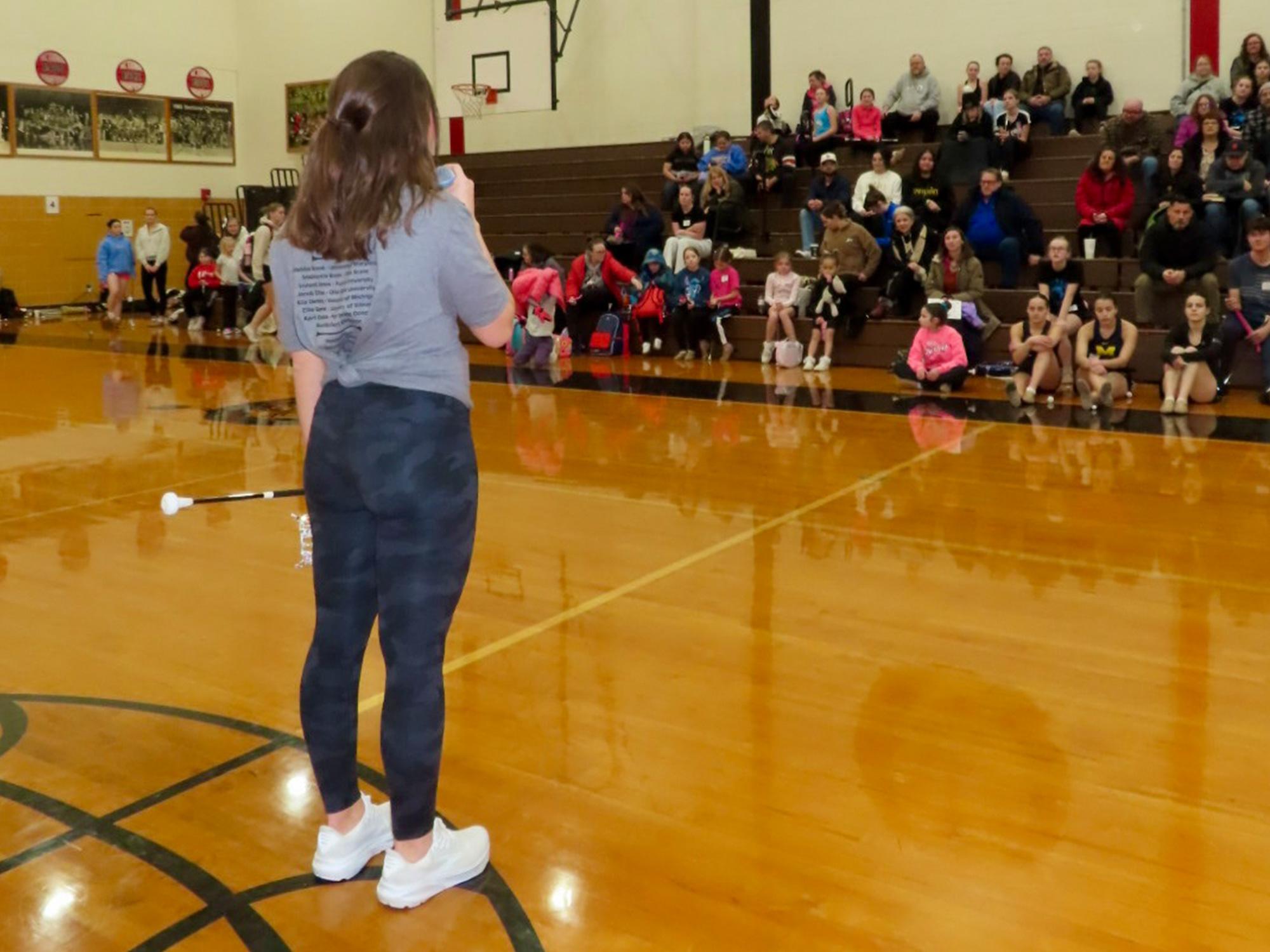 A woman speaks to a group of people on bleachers.