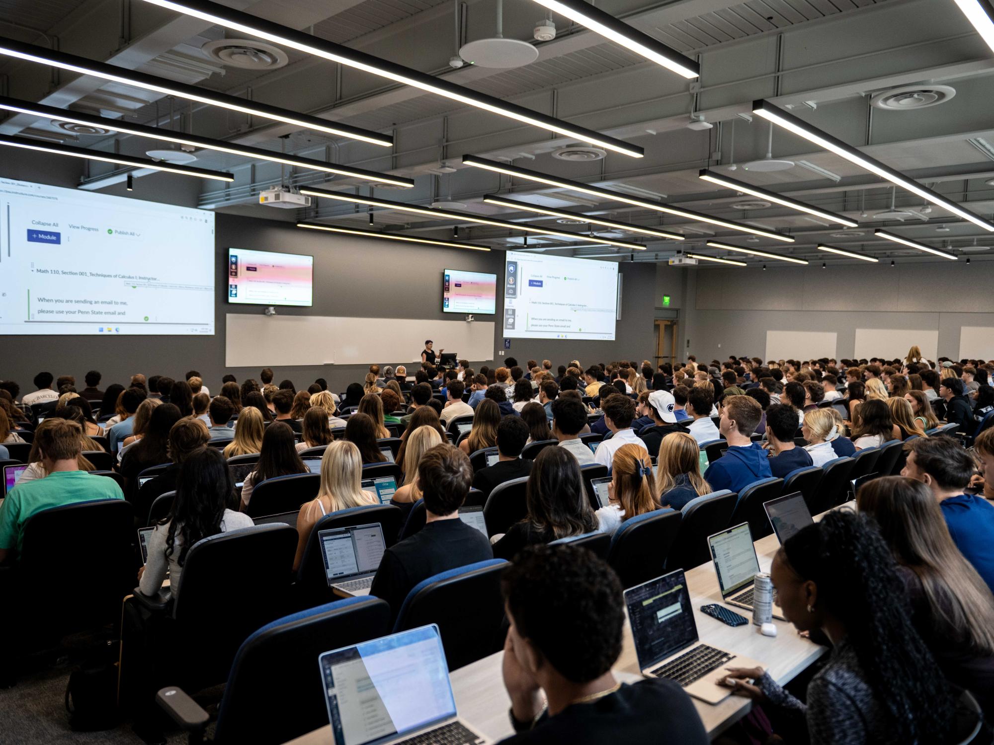 Students fill a large lecture hall with laptops open as an instructor leads a class on the first day of the fall semester at Penn State University Park.