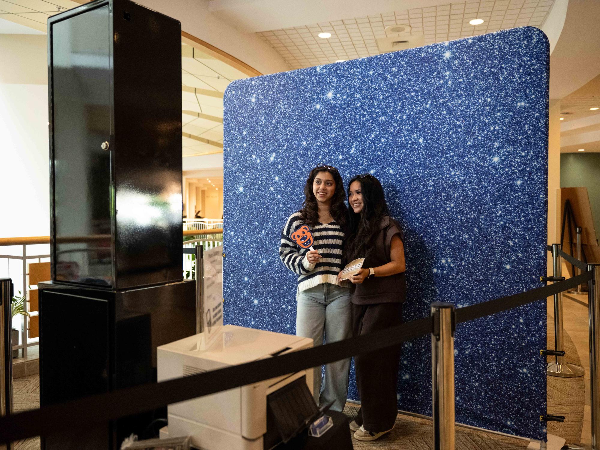 wo students pose for a photo in front of a blue, starry backdrop at a Blue & White Photo Booths setup inside the HUB-Robeson Center on the first day of fall classes.