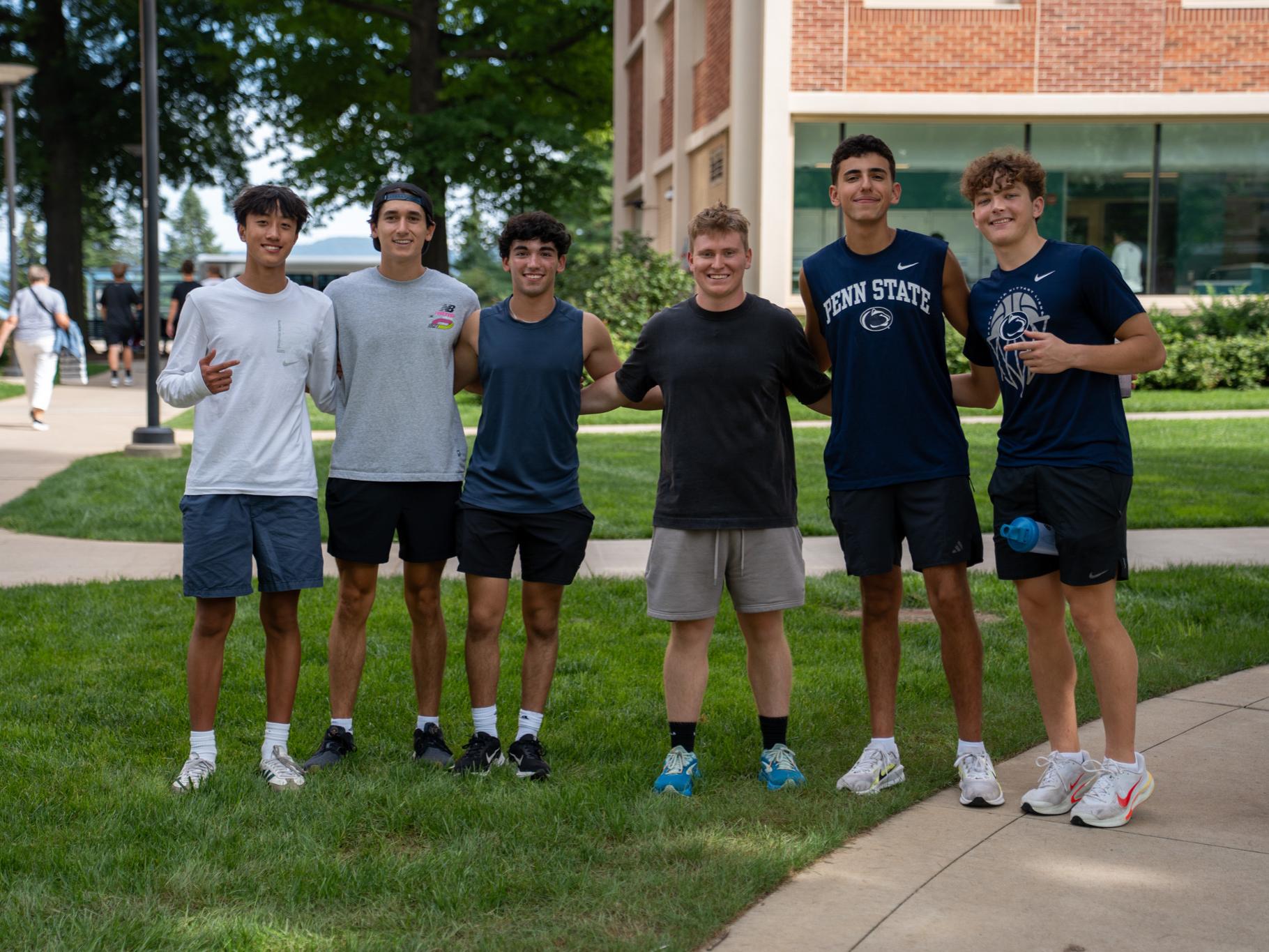 Six Penn State students pose together on a grassy area outside a campus building on the first day of the fall semester.
