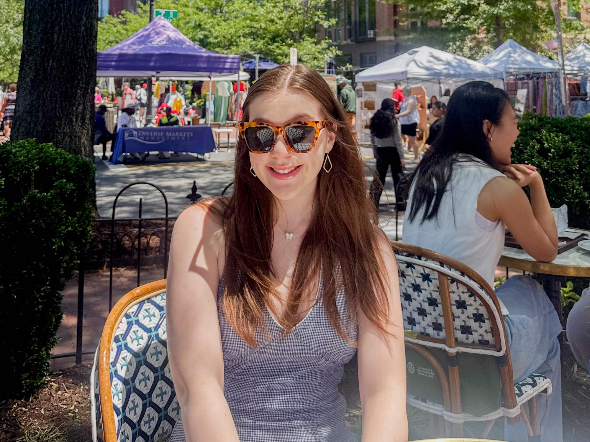 Ella Bartnik wears sunglasses and a navy top sitting at Eastern Market. 