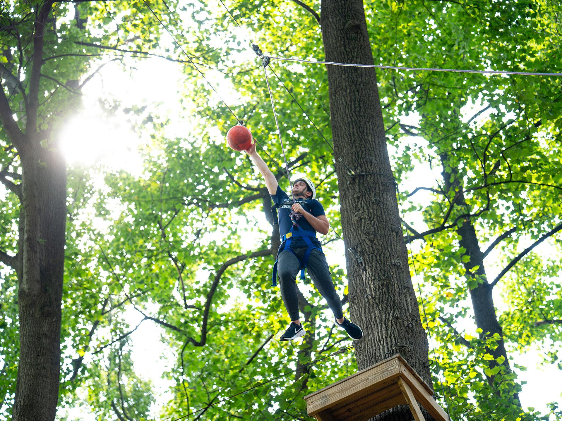 man hanging from a rope and reaching for a ball