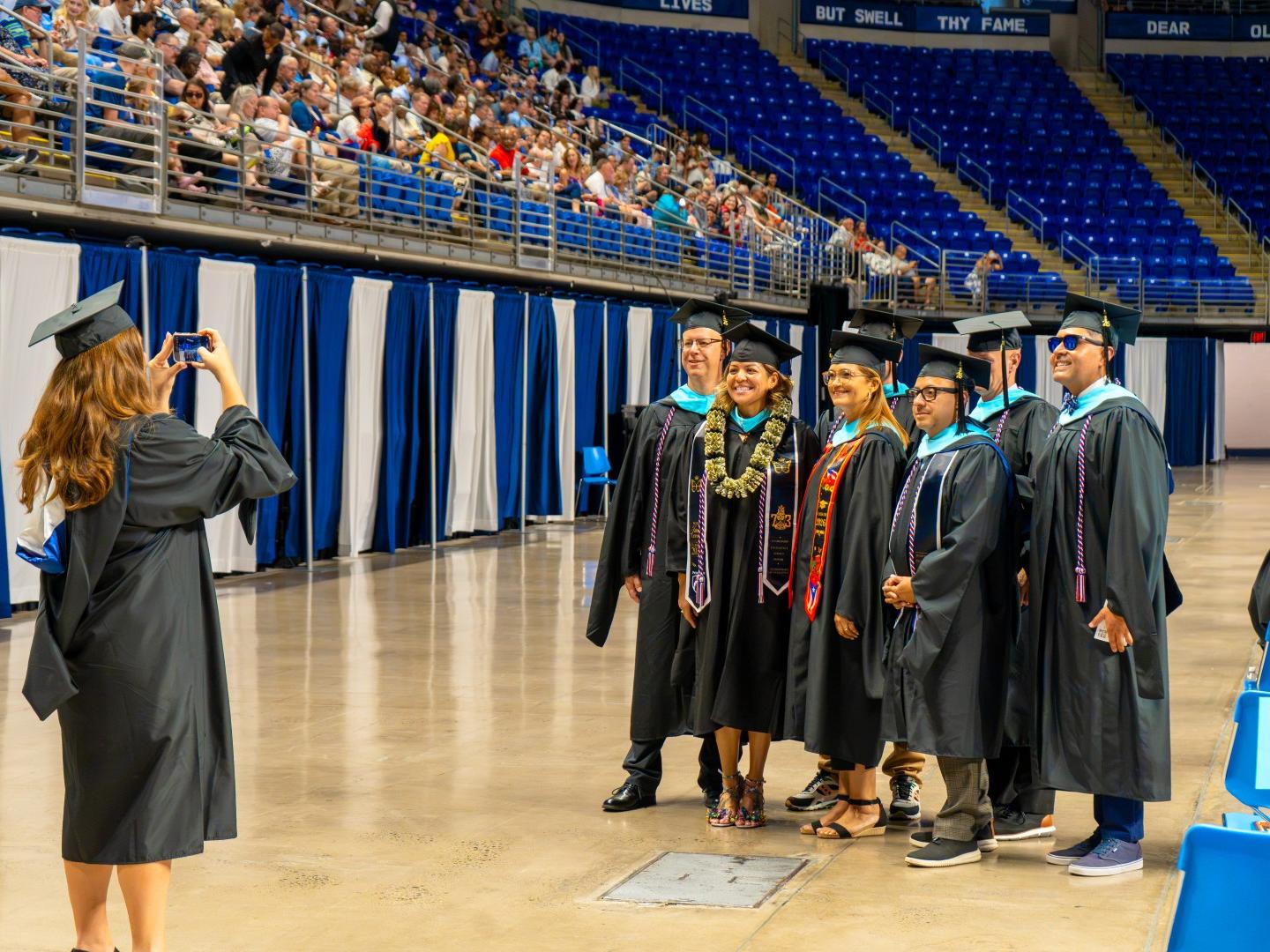 A group of graduates wearing black caps and gowns pose for a picture