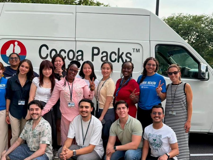 A group of diverse students stands together in front of a Cocoa Packs van.