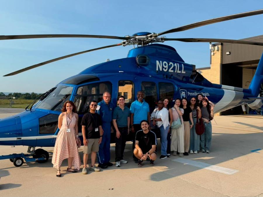 A group of students stands in front of a Life Lion helicopter.