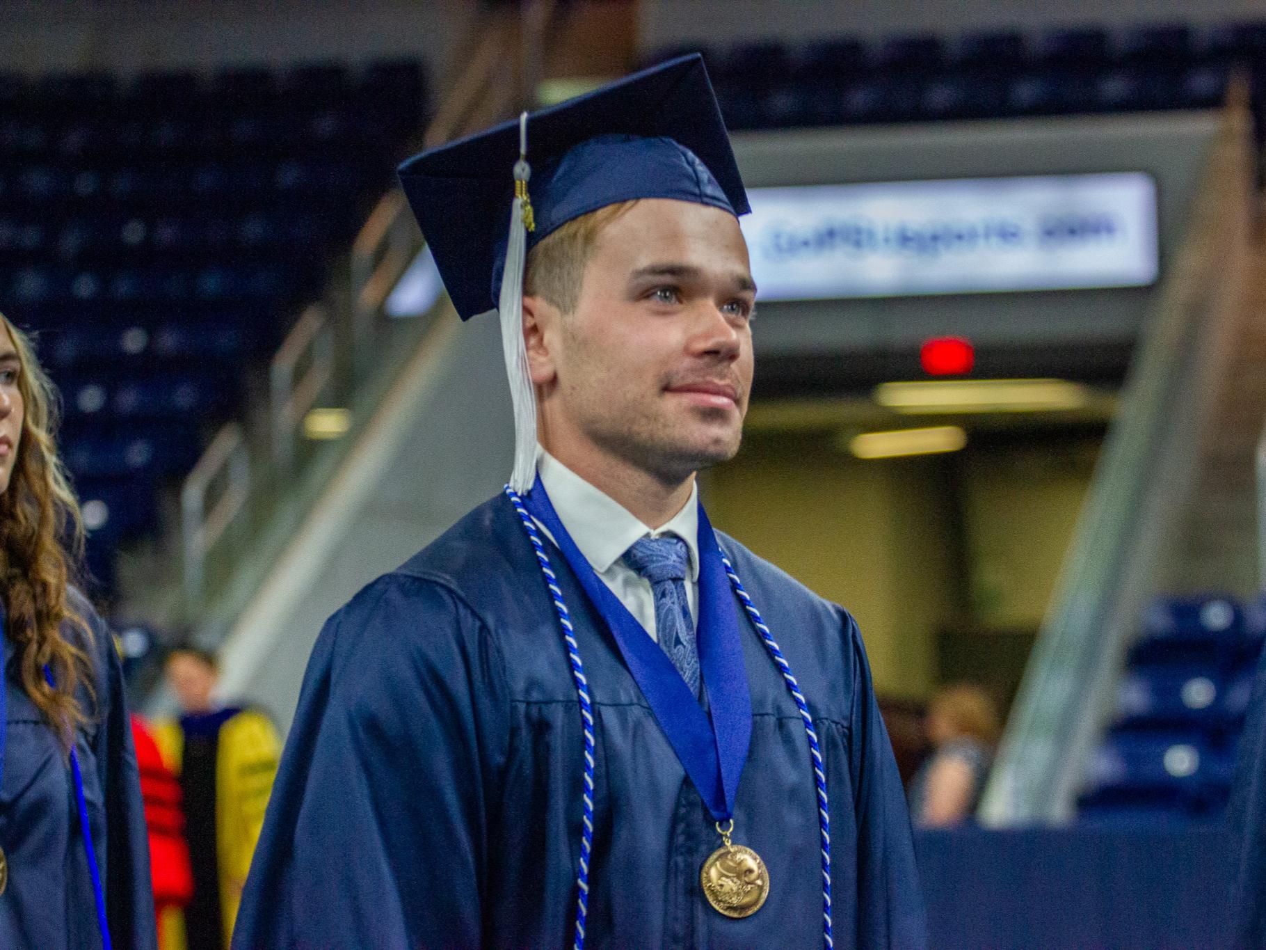 Nate in dark blue cap and gown during a graduation ceremony.