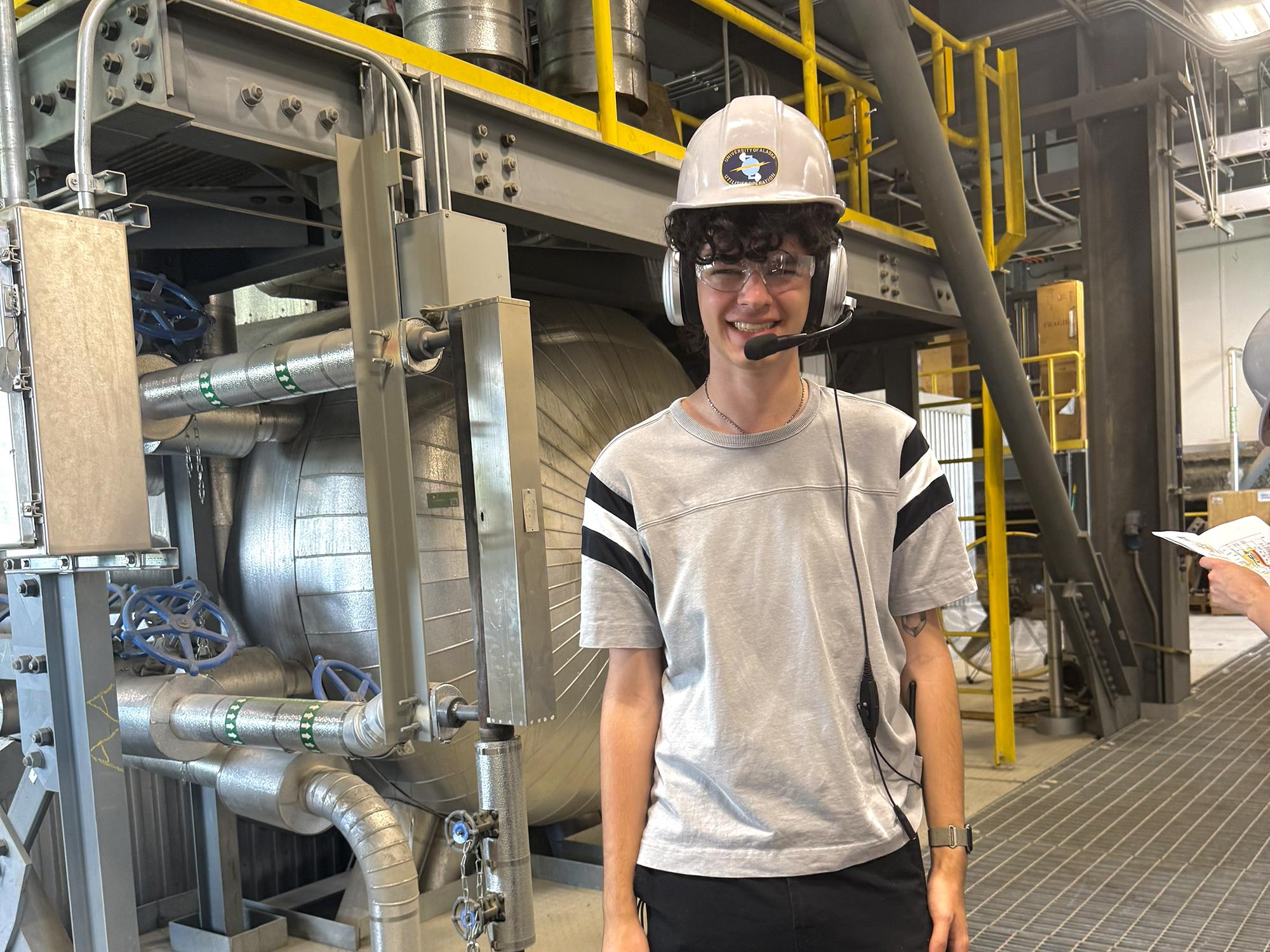 Undergraduate college student stands next to nine-story coal boiler at heat and power plant