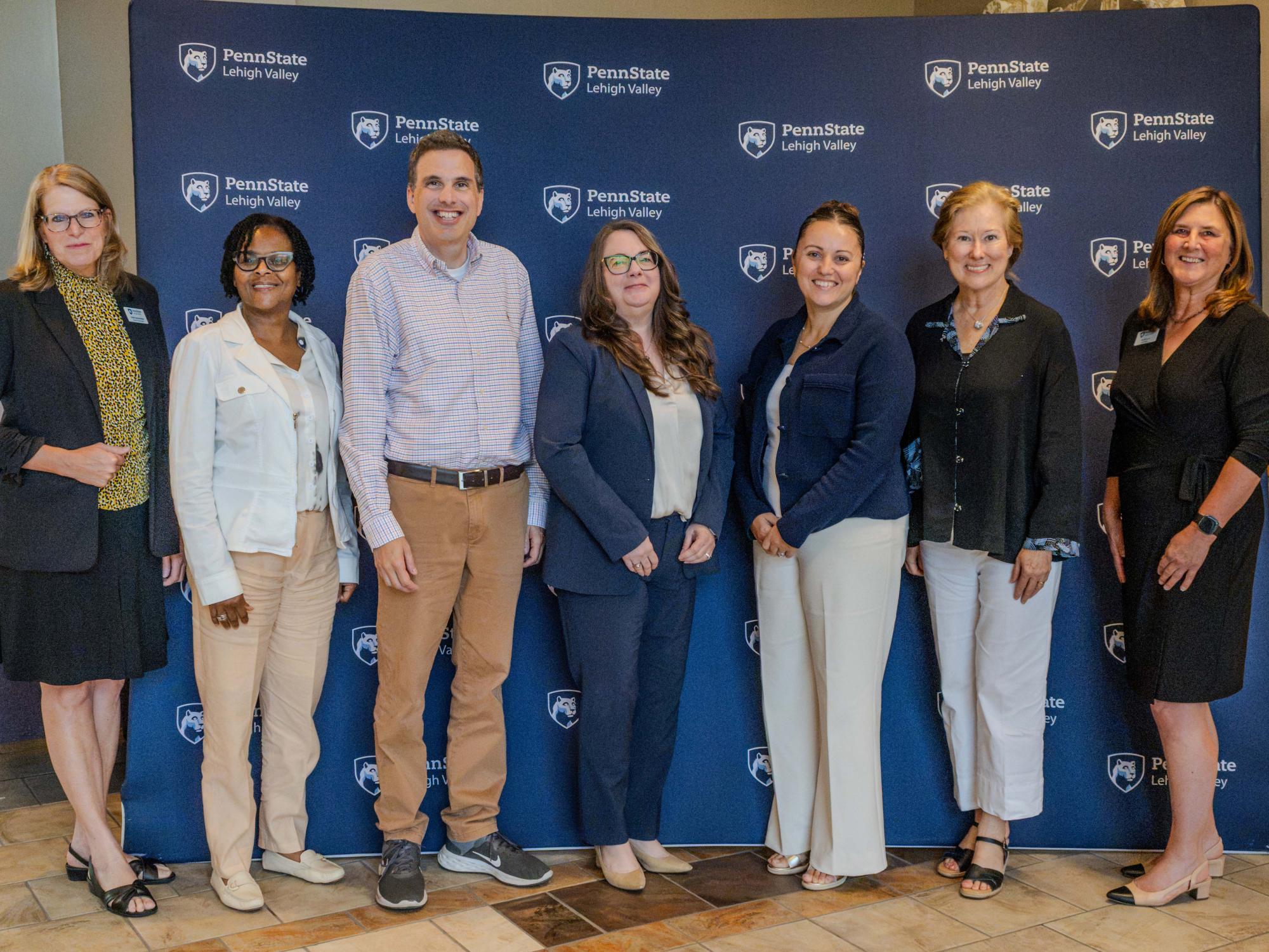 group of people standing in front of a penn state lehigh valley backdrop