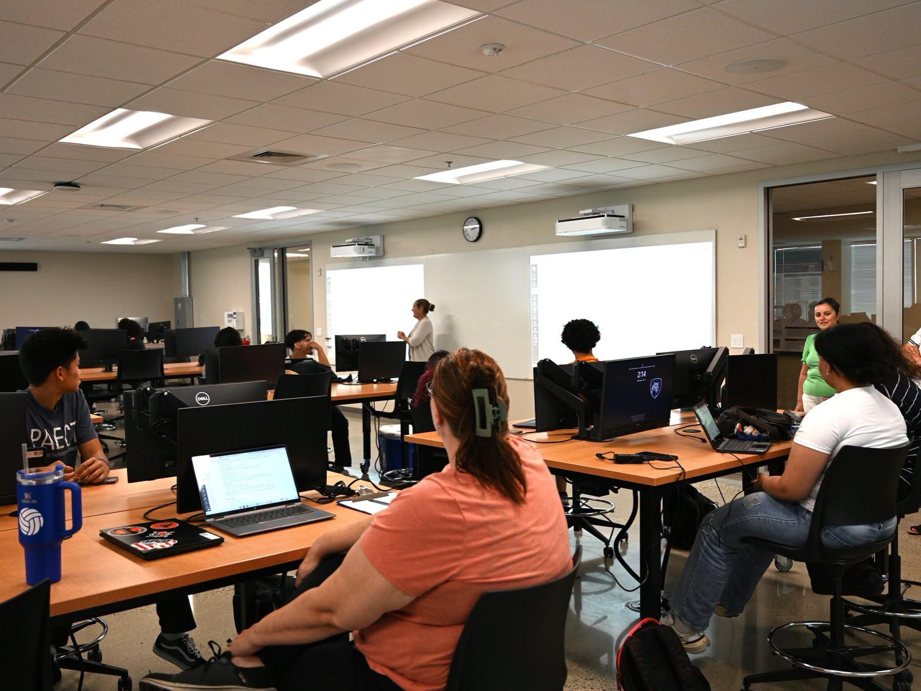 students in a classroom sitting in front of computers