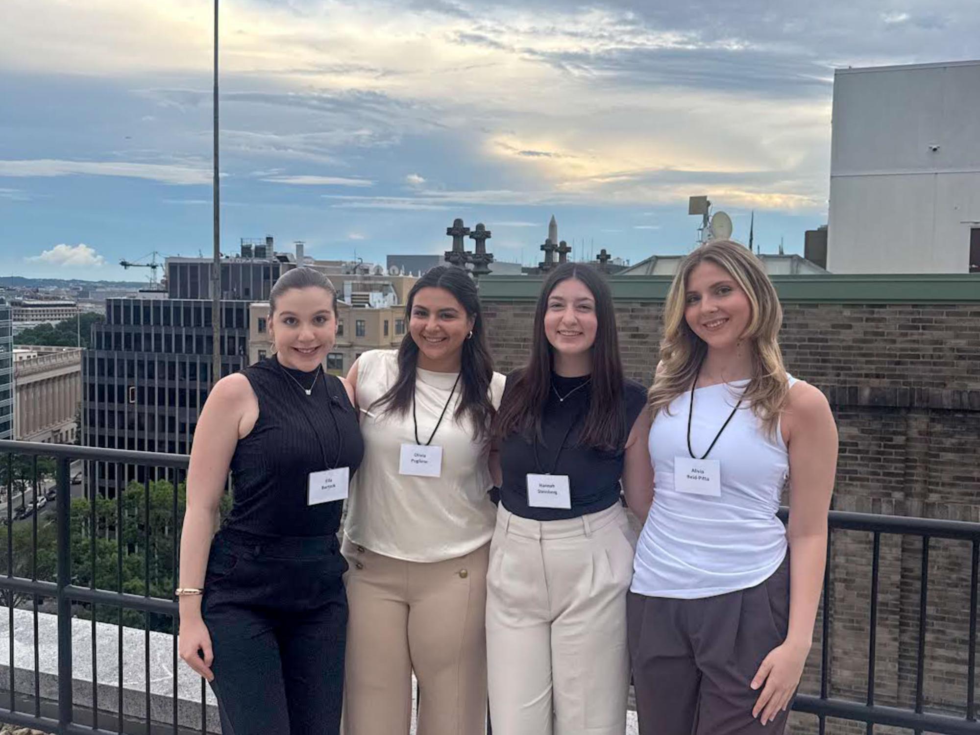 Reid-Pitta stands on the right side wearing a white top and brown pants standing on a rooftop. 