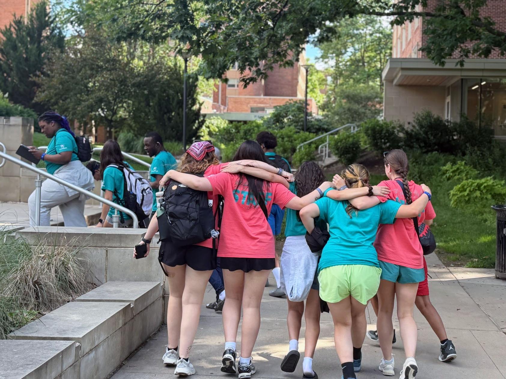 Summer Academy participants and staff walk together along a tree-lined path on Penn State’s University Park campus on their way to dinner.