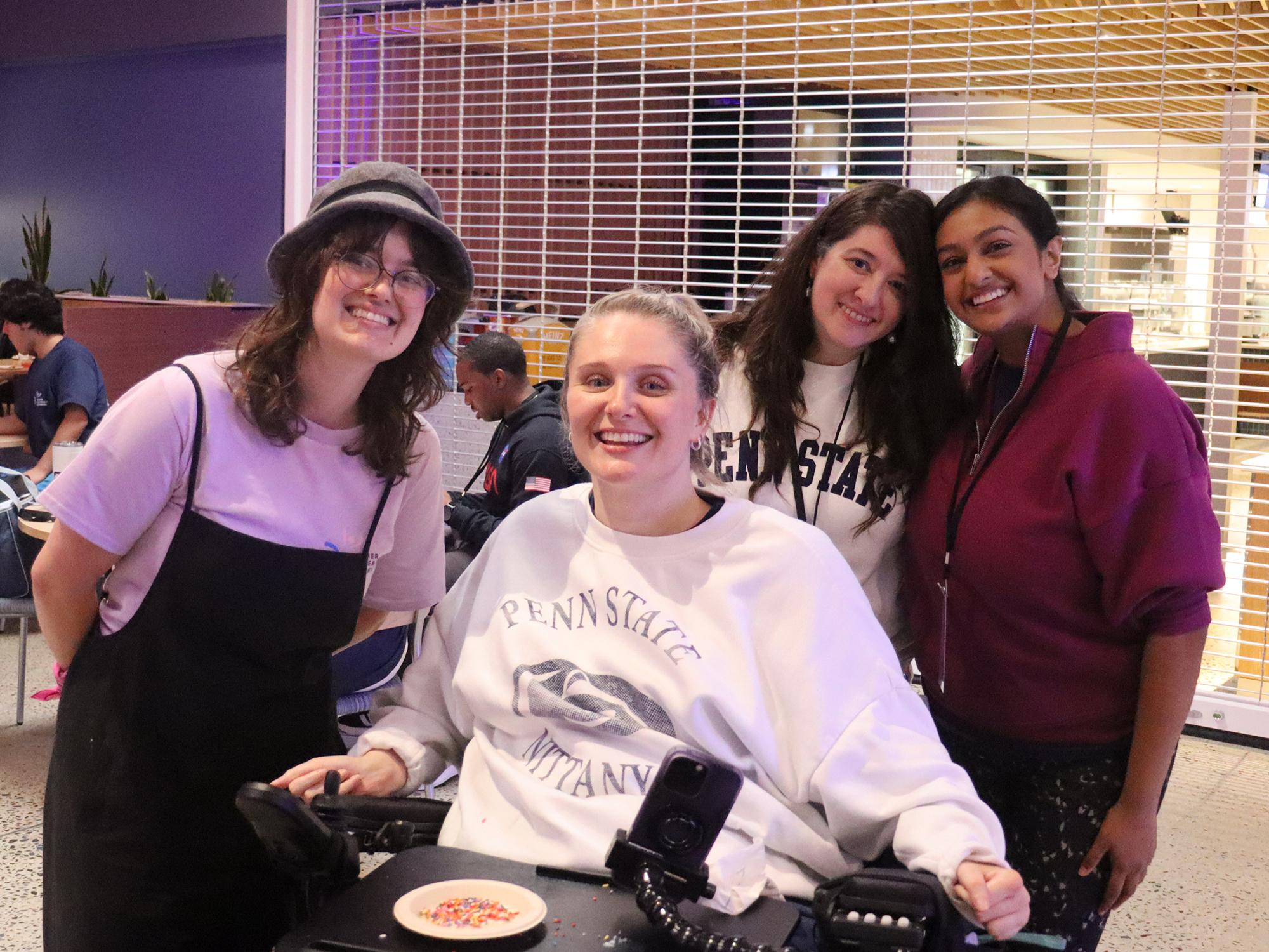Four women pose for a photo in a cafeteria.
