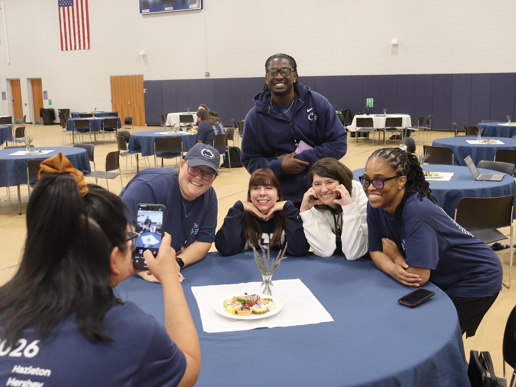 A woman takes a photo of a group of people sitting around a table.