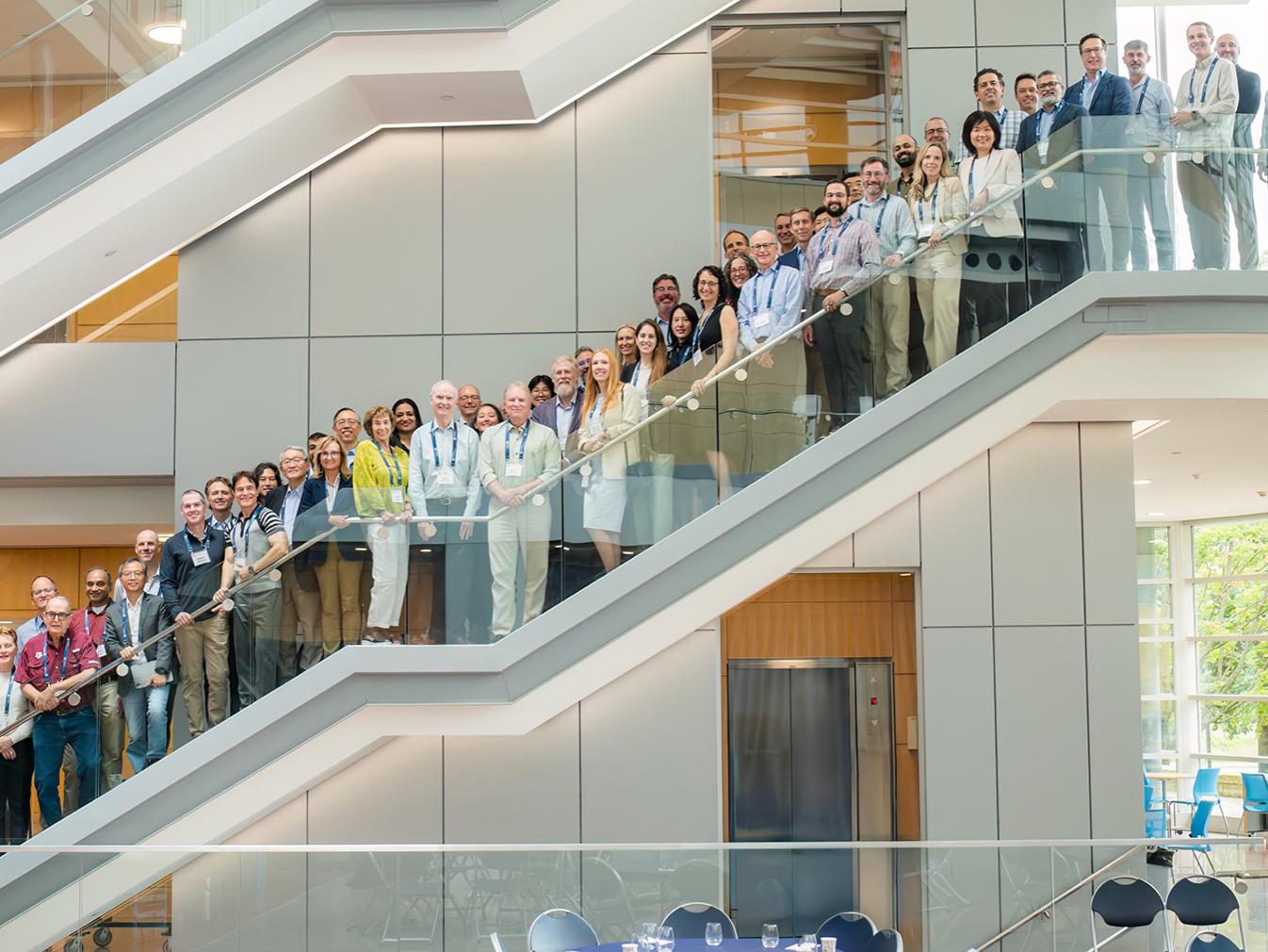 A group of people post on the stairs in the Penn State Business Building Atrium.