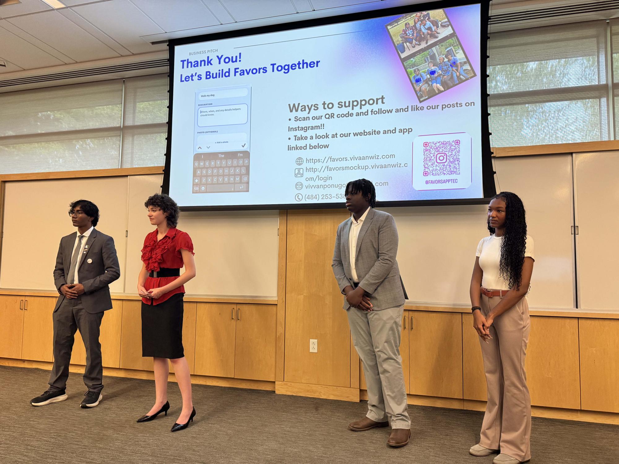 four students standing in front of a projection screen