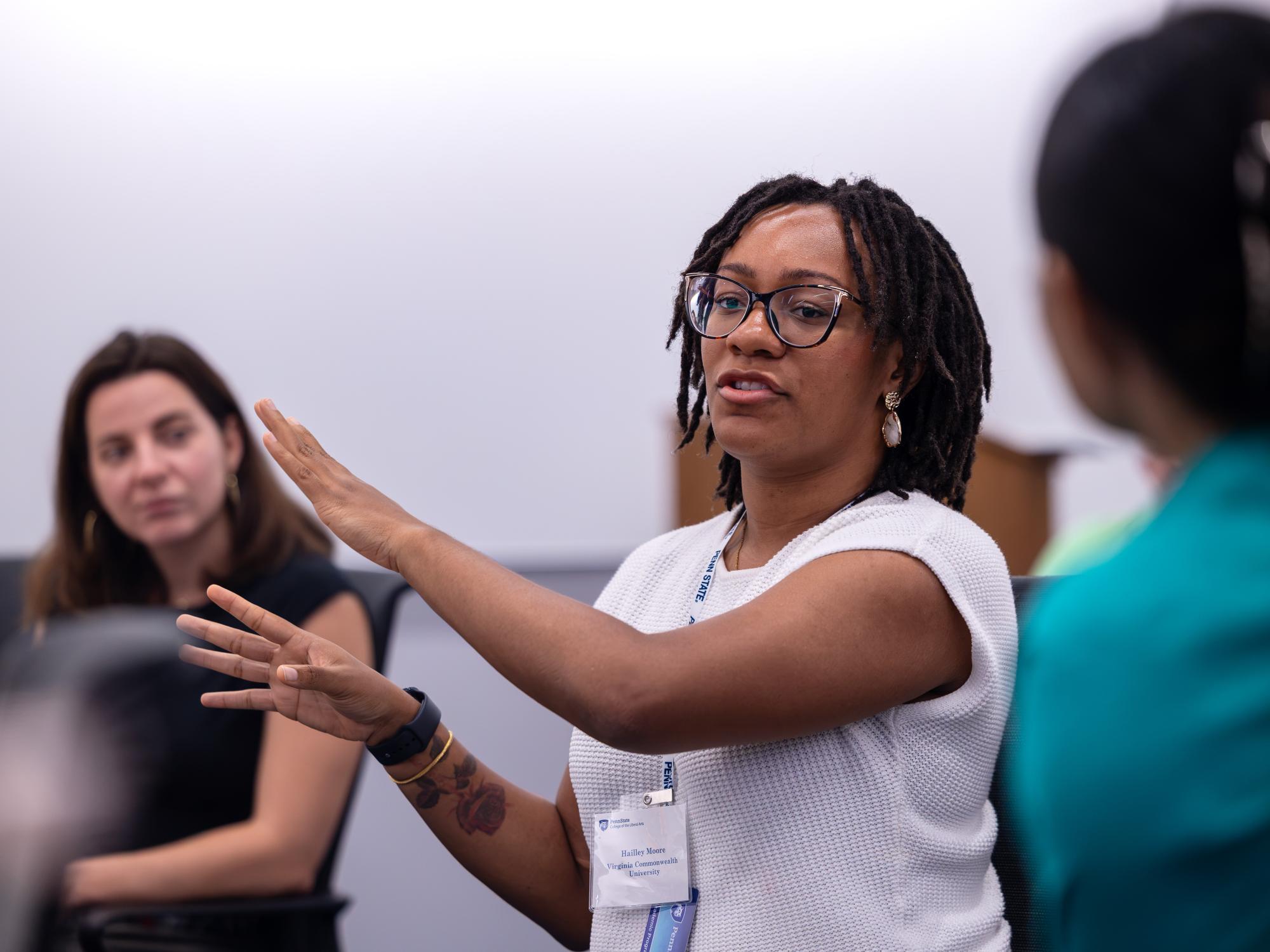 Hailley Moore wears a white blouse and makes a point while using her arms for emphasis. 