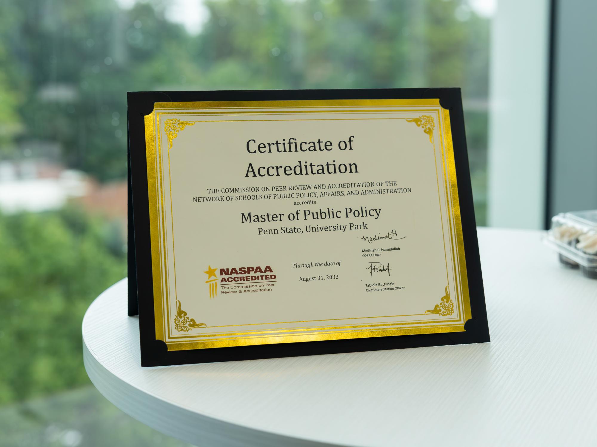 Certificate of accreditation for the School of Public Policy sits on a table. 