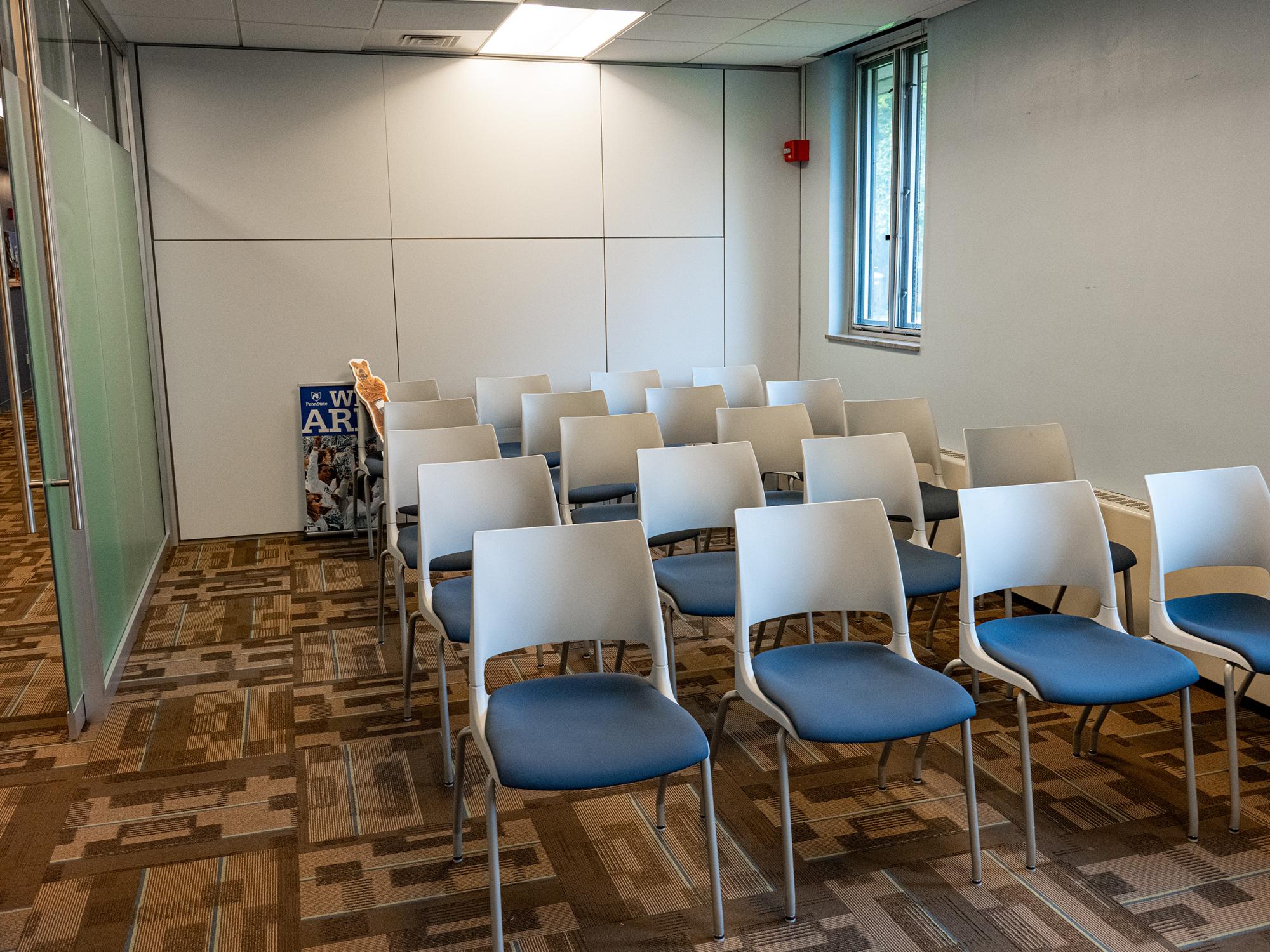 A meeting room in the Admissions and Student Aid suite features rows of white and blue chairs, modern finishes, and large windows providing natural light.