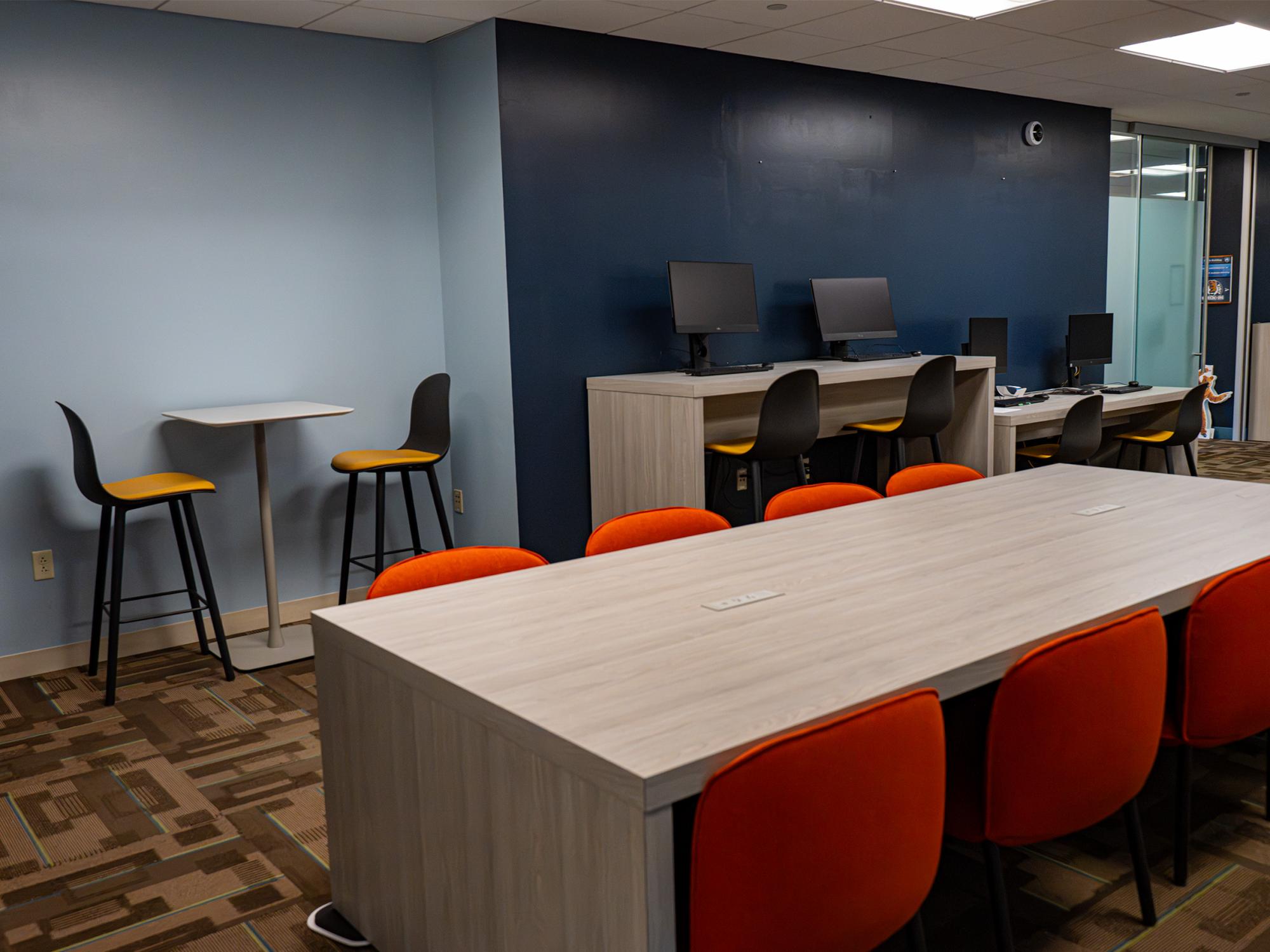 A renovated workspace in the Admissions and Student Aid suite features collaborative tables, computer stations, and modern seating in Penn State colors.